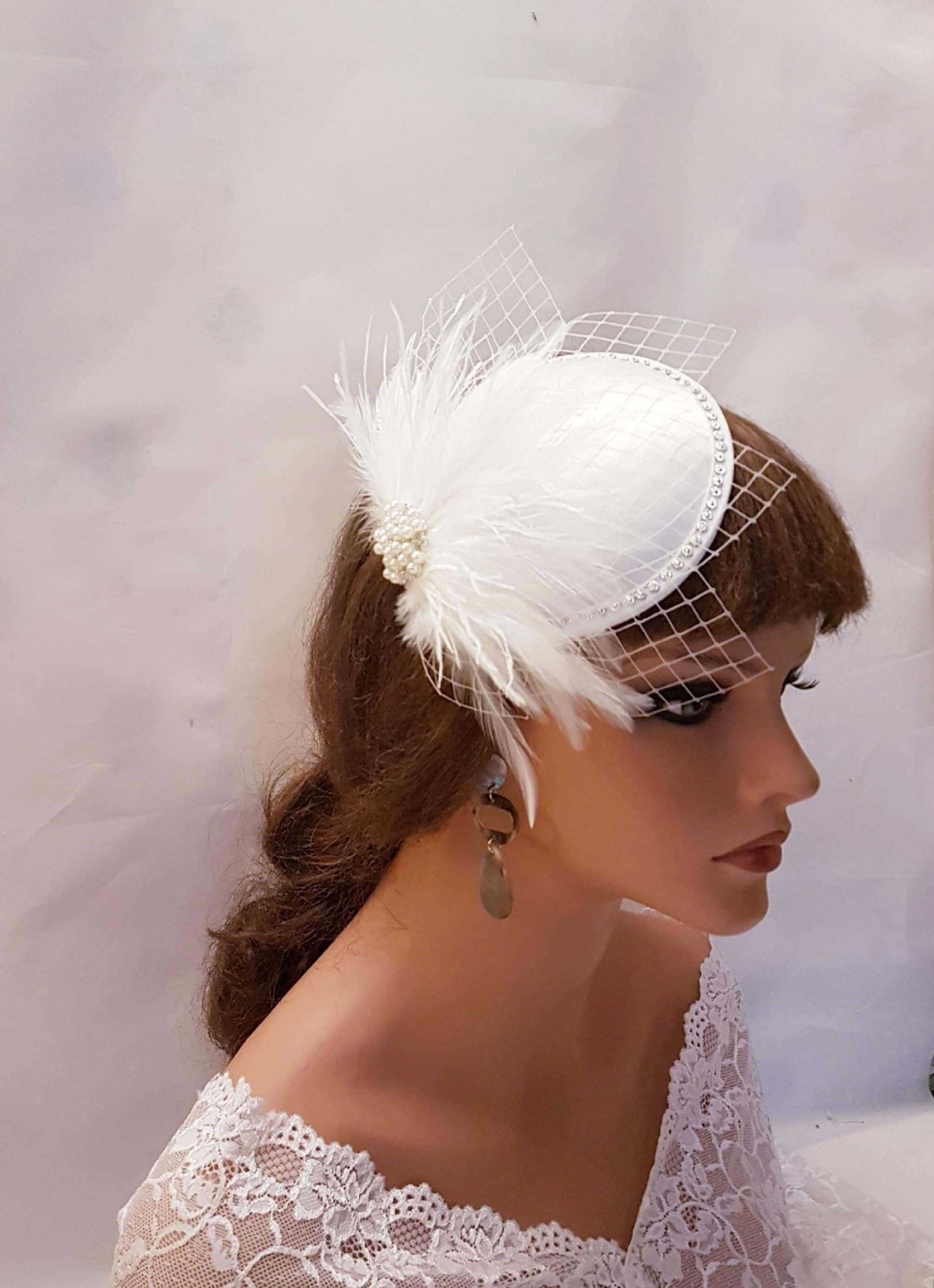 White ivory bridal feather fascinator hat with French netting and crystal jewel.
