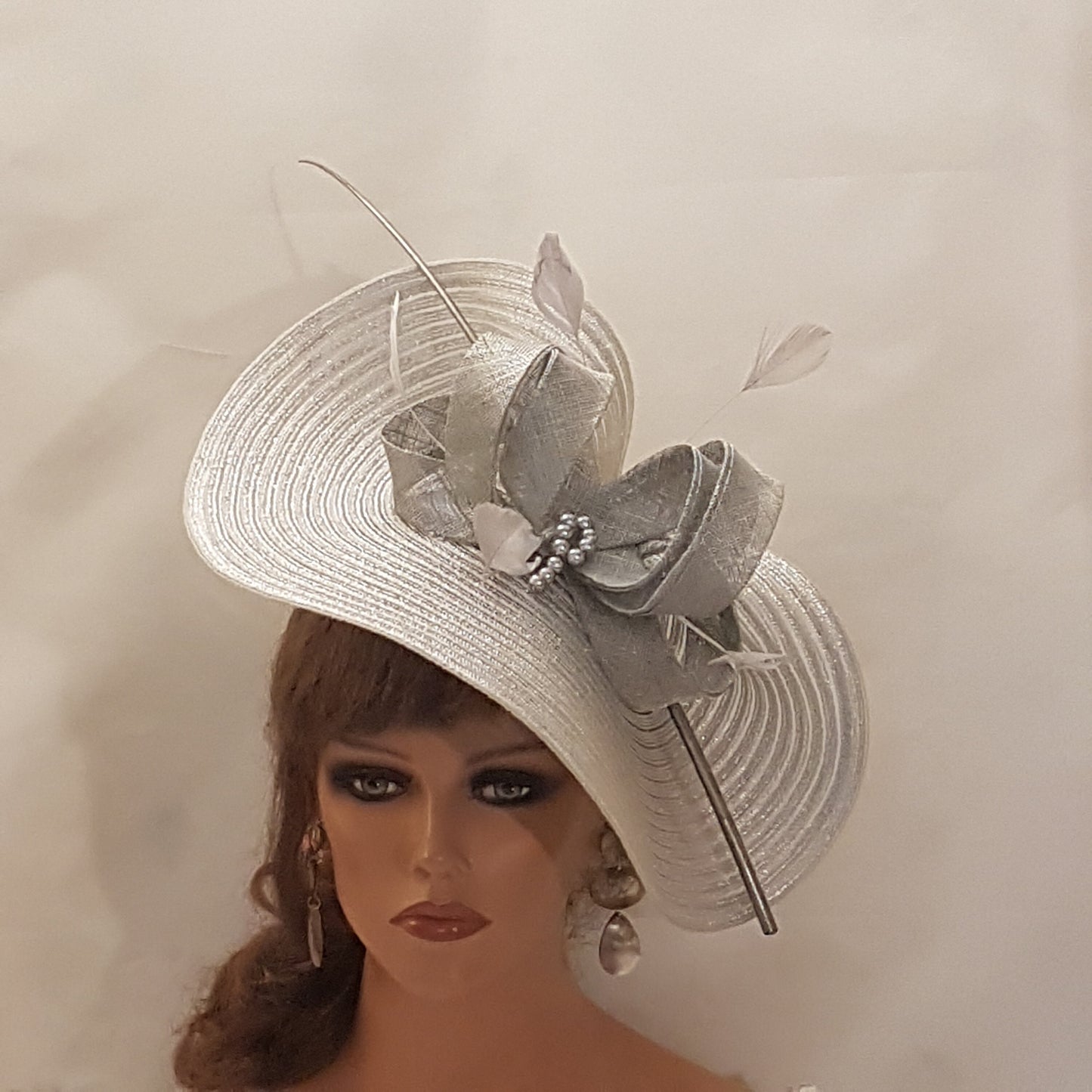 Elegante cappello largo fascinator in argento metallizzato con piume, perle, fiocco. Sofisticato copricapo da sposa, cappello per la madre della sposa, accessorio di tendenza