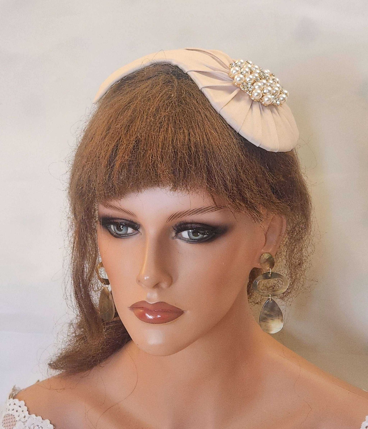 Bridal hat fascinator with pearl and crystal embellishments on mannequin.