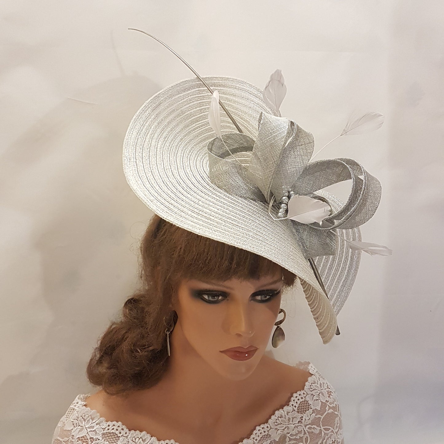 Elegante cappello largo fascinator in argento metallizzato con piume, perle, fiocco. Sofisticato copricapo da sposa, cappello per la madre della sposa, accessorio di tendenza