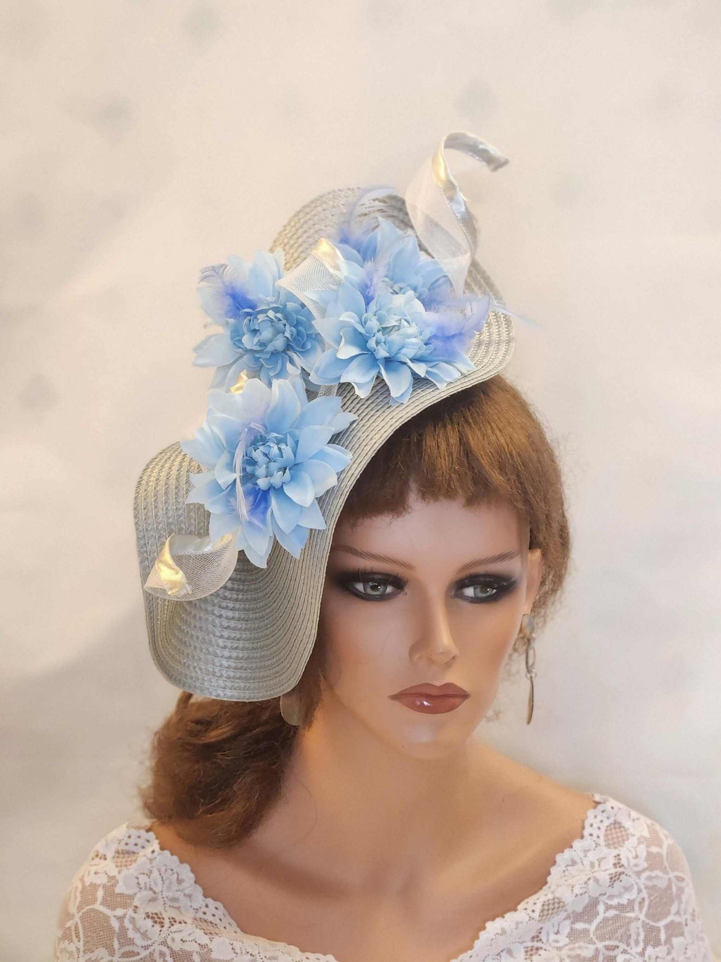 Silver and blue fascinator with feathers and flowers, perfect for weddings and special occasions.