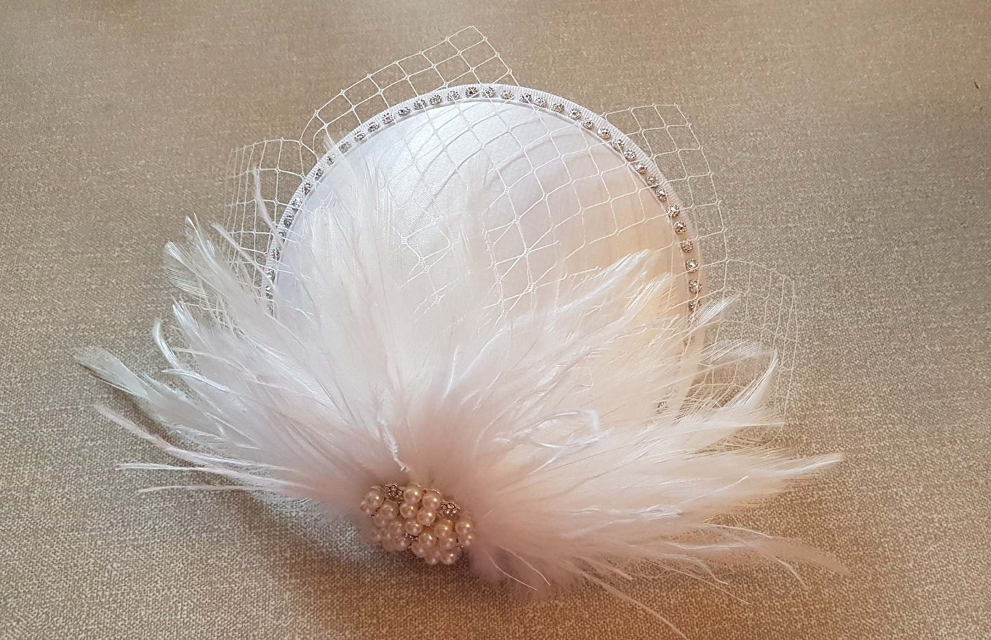 White Ivory feather bridal fascinator with French netting and jewel embellishment.