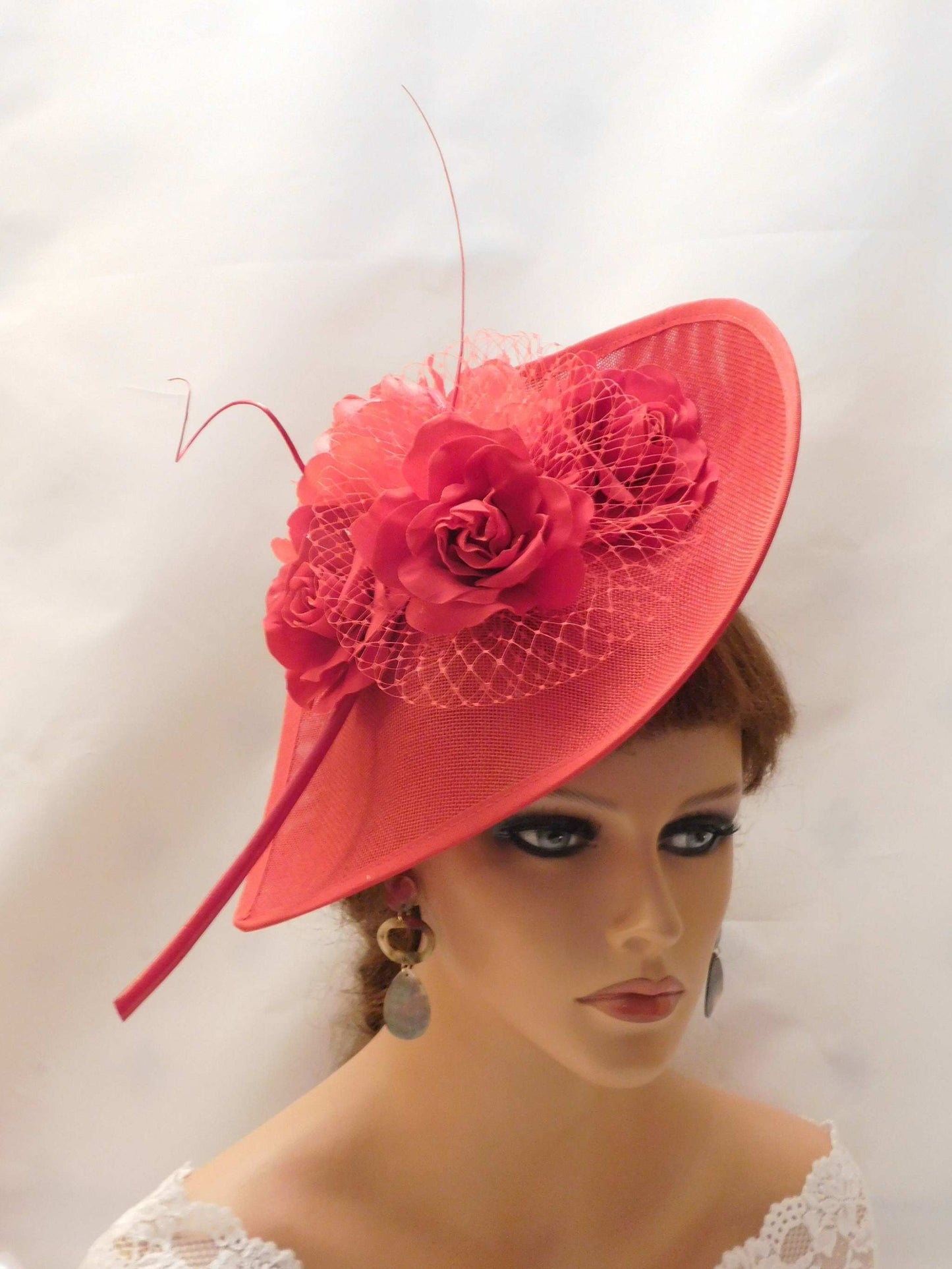 Red fascinator hat with velvet roses, peony flower, quill feather, and French netting on mannequin head