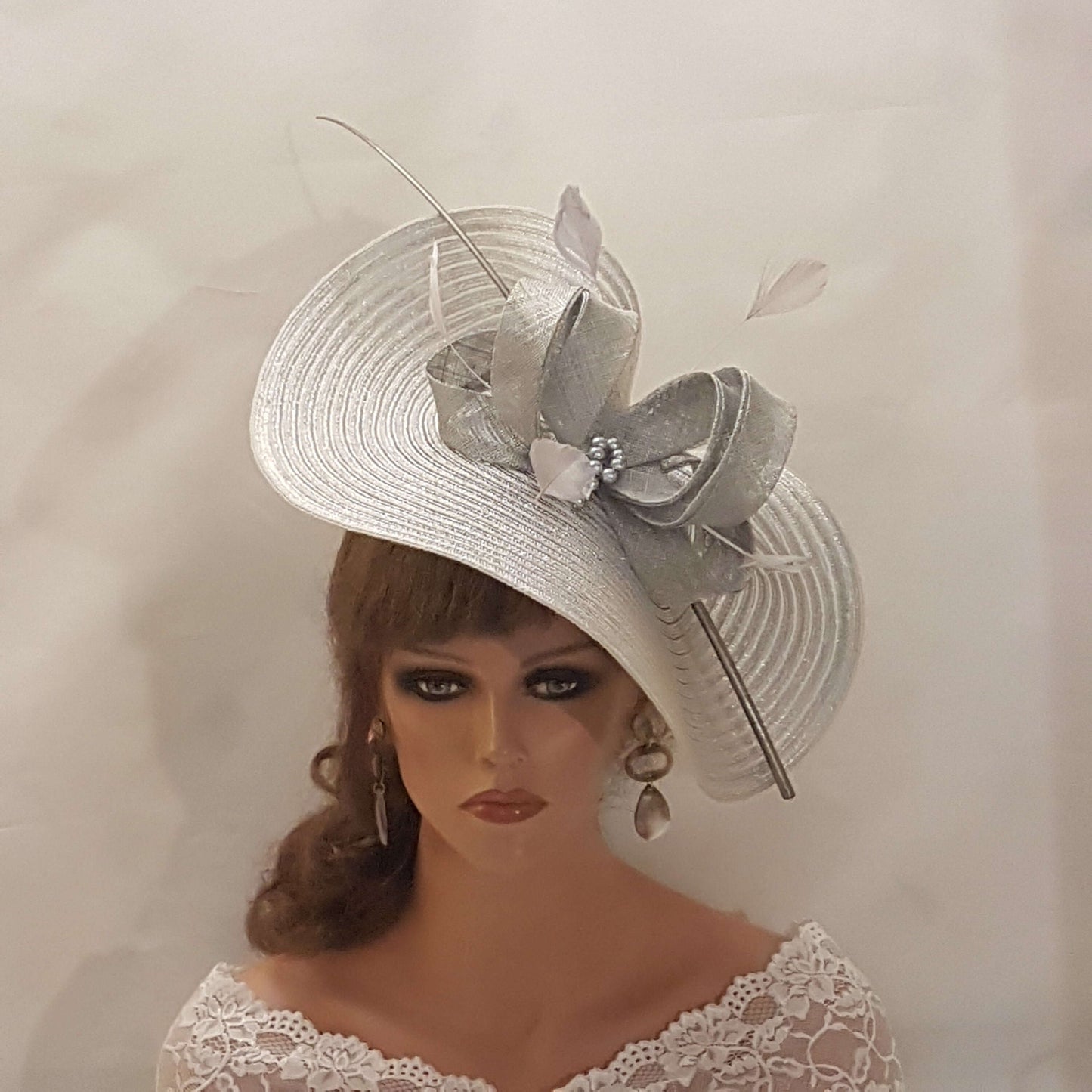 Elegante cappello largo fascinator in argento metallizzato con piume, perle, fiocco. Sofisticato copricapo da sposa, cappello per la madre della sposa, accessorio di tendenza