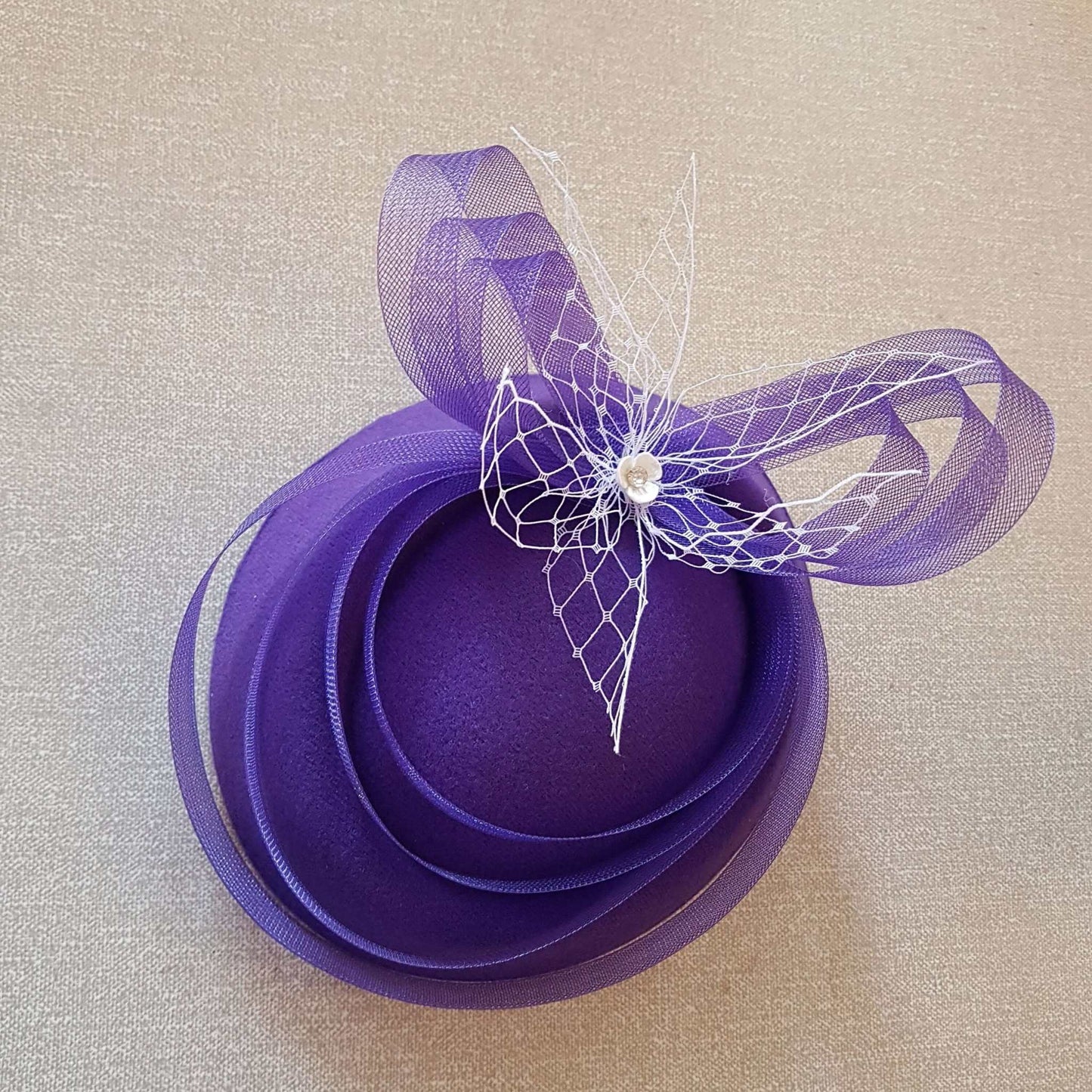 Purple fascinator hat with crinoline bows and net detail.