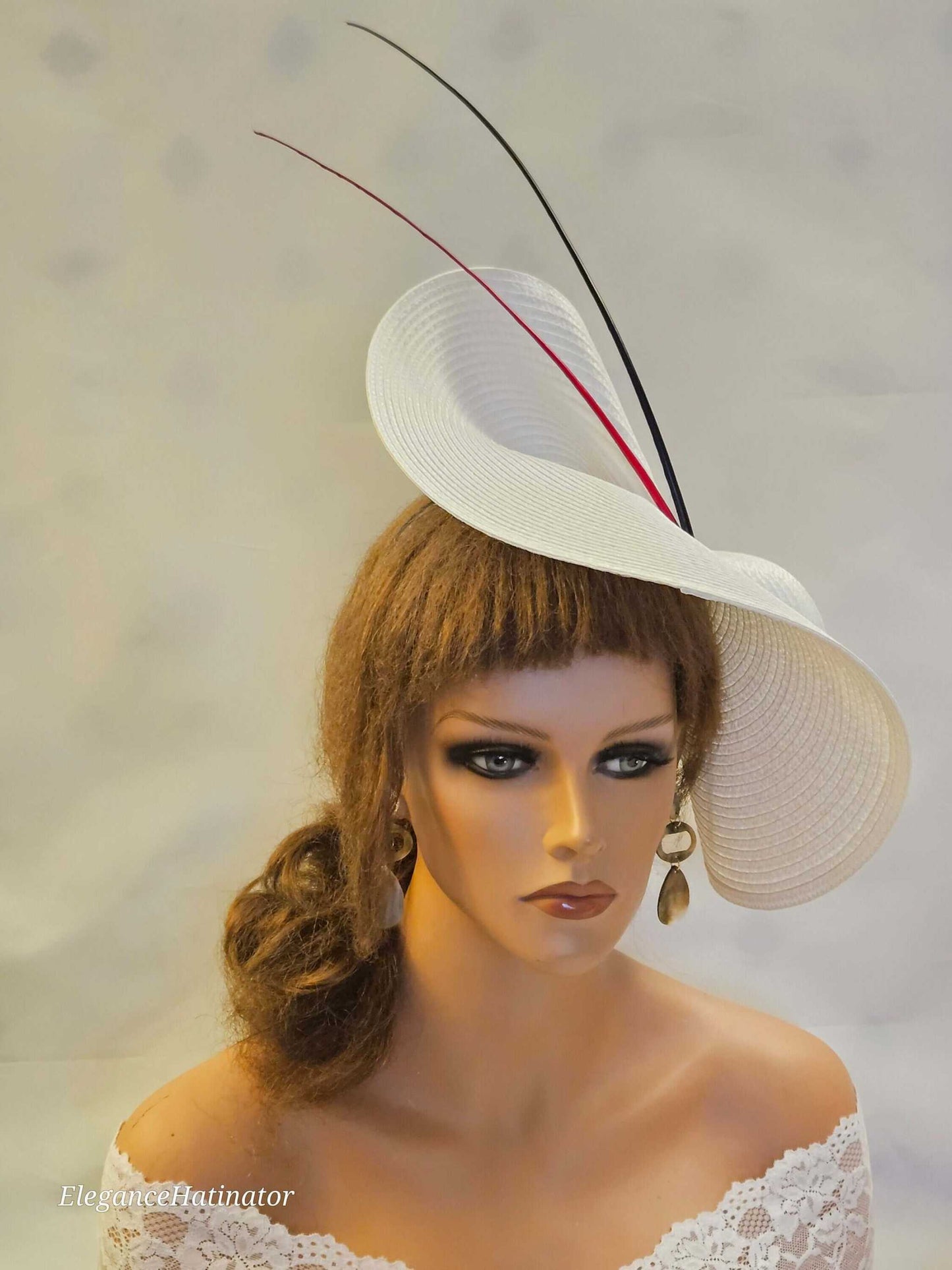 Large white saucer hatinator with red and black quill feathers for weddings and special occasions.