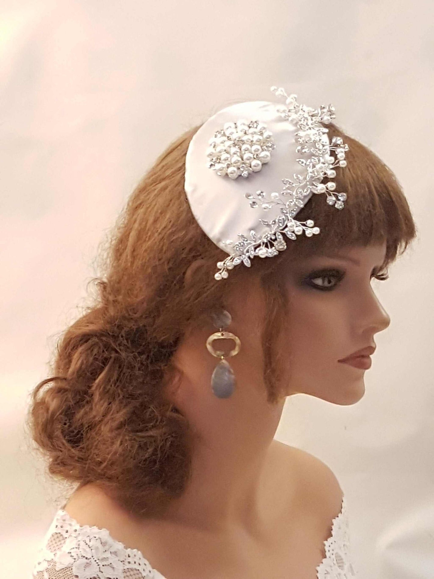 Bridal fascinator with teardrop hat, birdcage veil, and crystal embellishments.