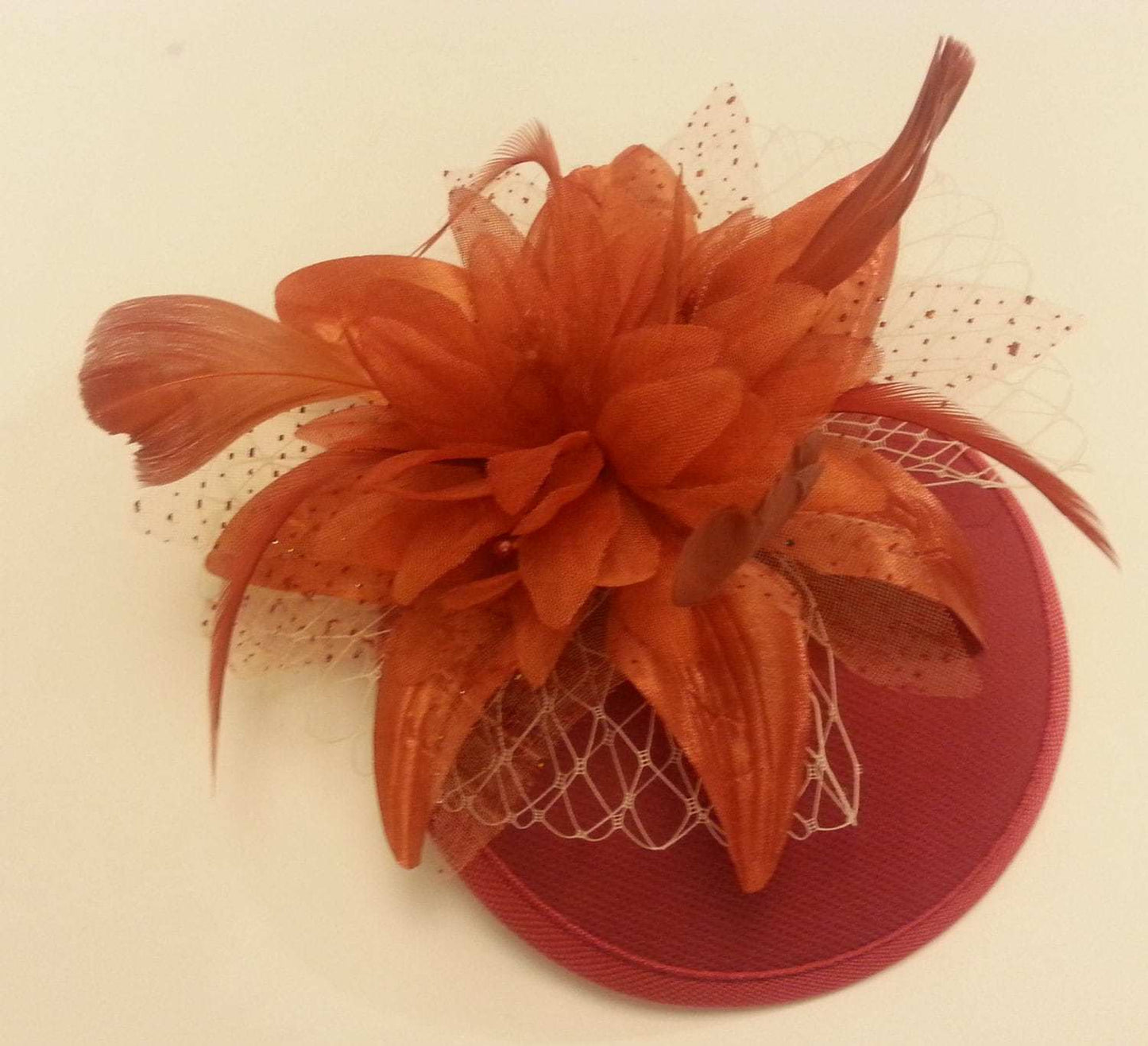 Vintage terracotta rusty fascinator hat with feather flower and French net bow for weddings and races
