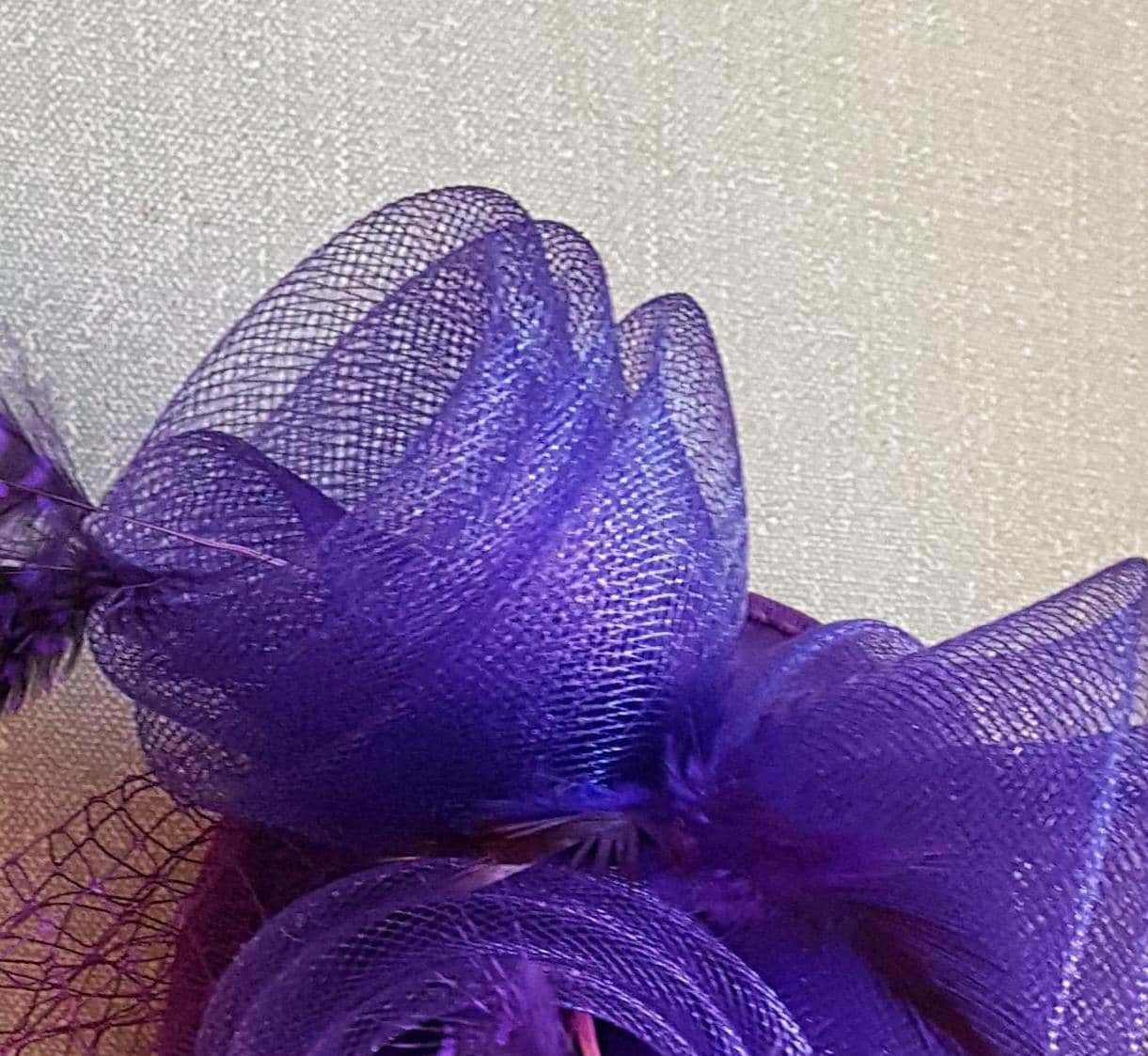 Bridal birdcage veil hat fascinator with purple crinoline roses and feathers.