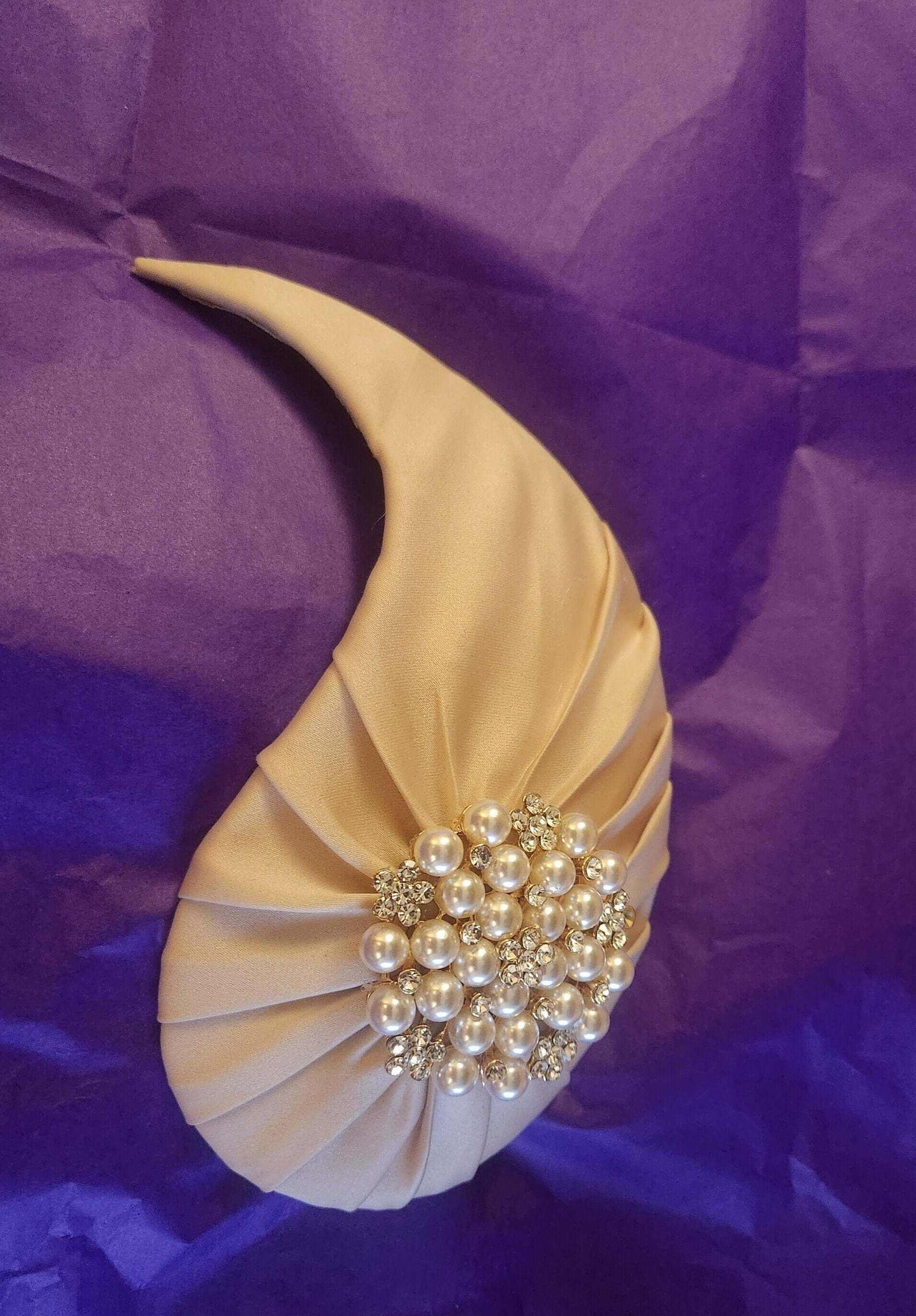 Bridal hat fascinator with pearls and crystals on satin, elegant wedding accessory.