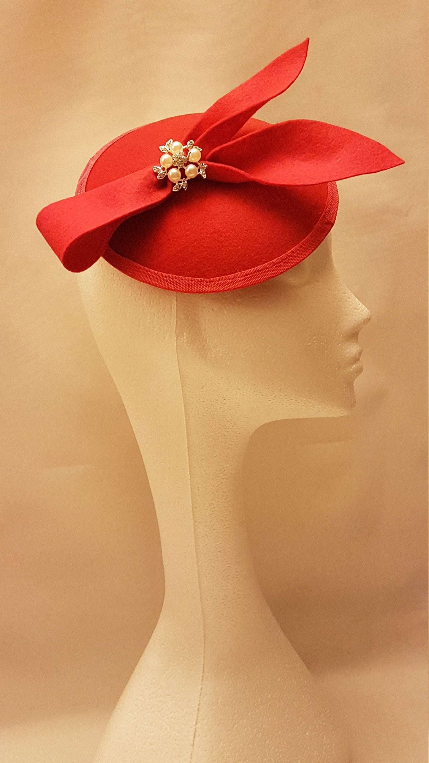Red fascinator hat with felt bow and crystal pearl jewel for weddings, races, and special occasions.