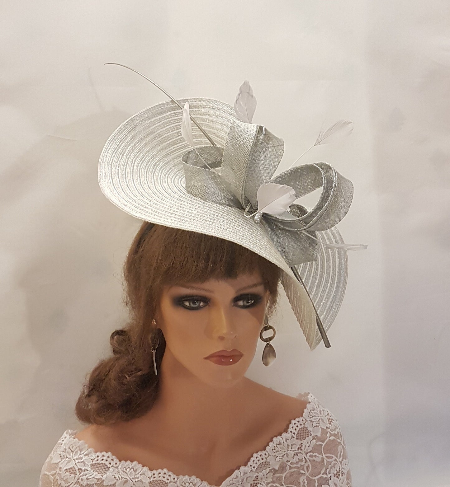 Elegante cappello largo fascinator in argento metallizzato con piume, perle, fiocco. Sofisticato copricapo da sposa, cappello per la madre della sposa, accessorio di tendenza