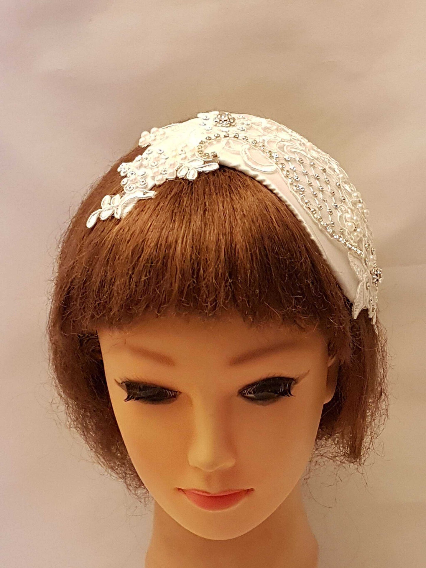 Bridal birdcage veil fascinator with crystals and pearls on a mannequin.