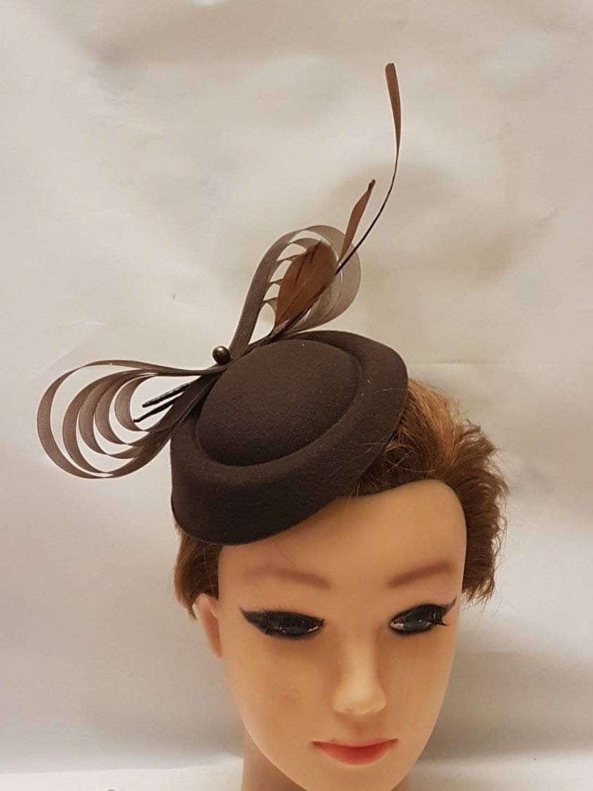 A brown felt like hat with a brown feather and ribbon accent.