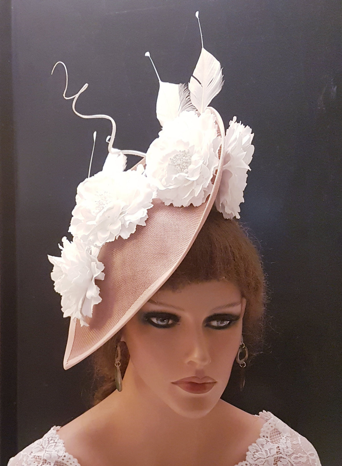 blush pink fascinator with white flower accents and feathers.