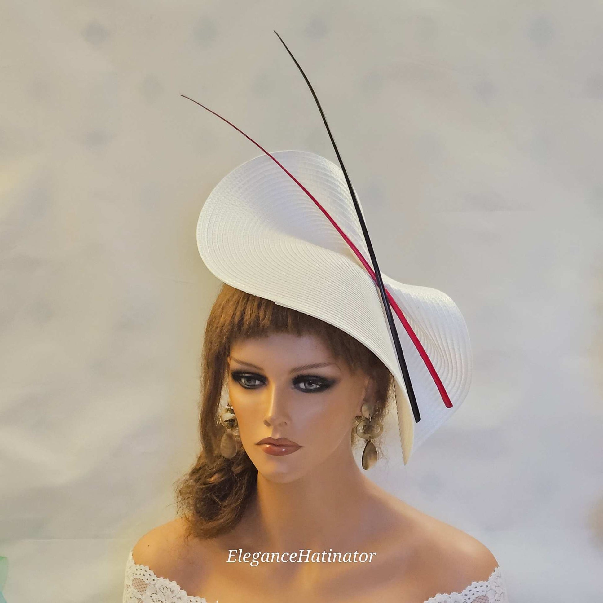 Large white saucer hatinator with red and black quill feathers for weddings and special occasions.