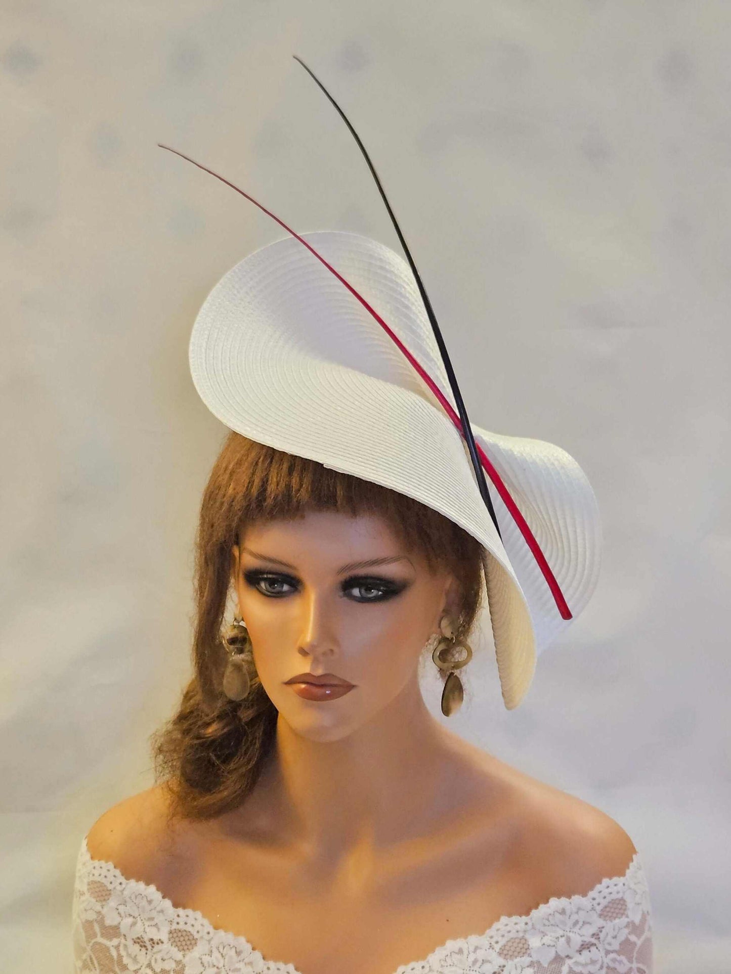 Large white saucer fascinator hat with red and black quill feathers for weddings and special occasions.