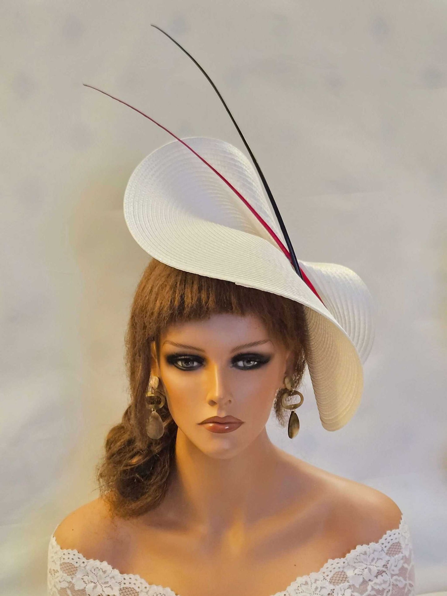 White saucer fascinator hat with red and black quill feathers for weddings and special occasions.