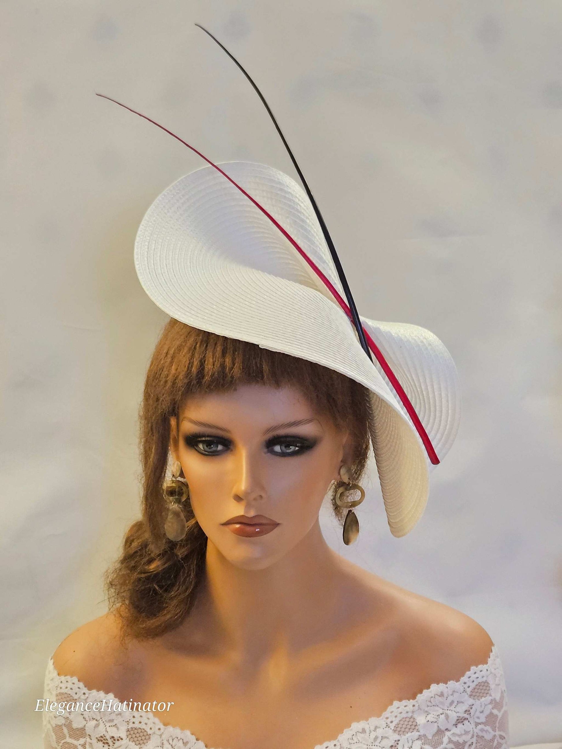 Large white saucer hatinator with red and black quill feathers for weddings and special occasions.