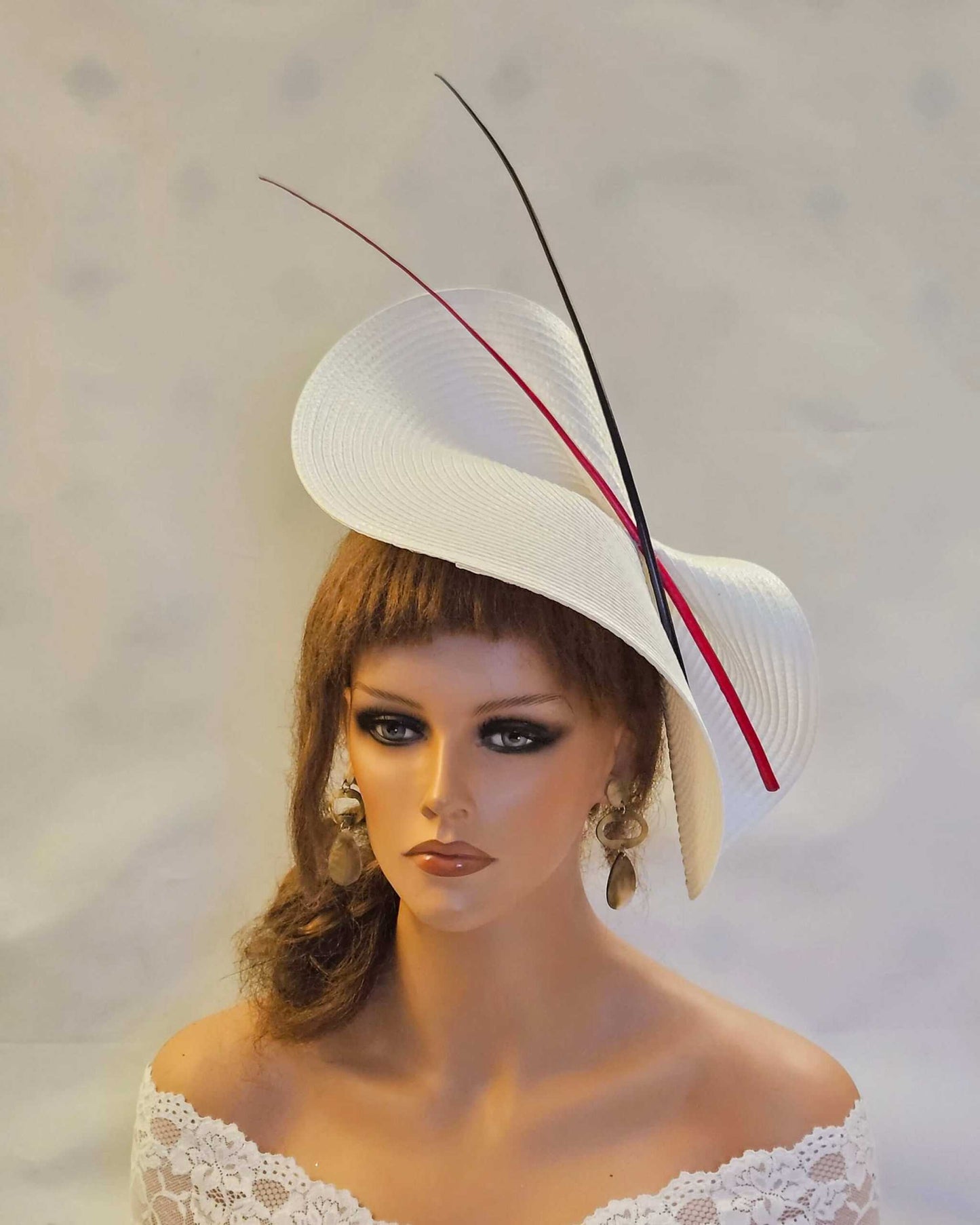 Large white saucer hatinator with red and black quill feathers for weddings and special occasions.