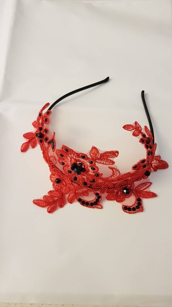 A red lace headband with black rhinestones. The headband is a delicate and feminine accessory.