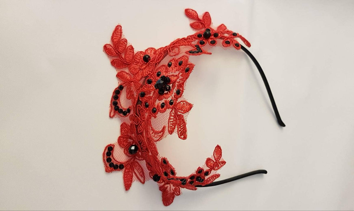 red lace headband with black bead embellishments. The headband is made of a delicate, floral lace and has a black elastic band.