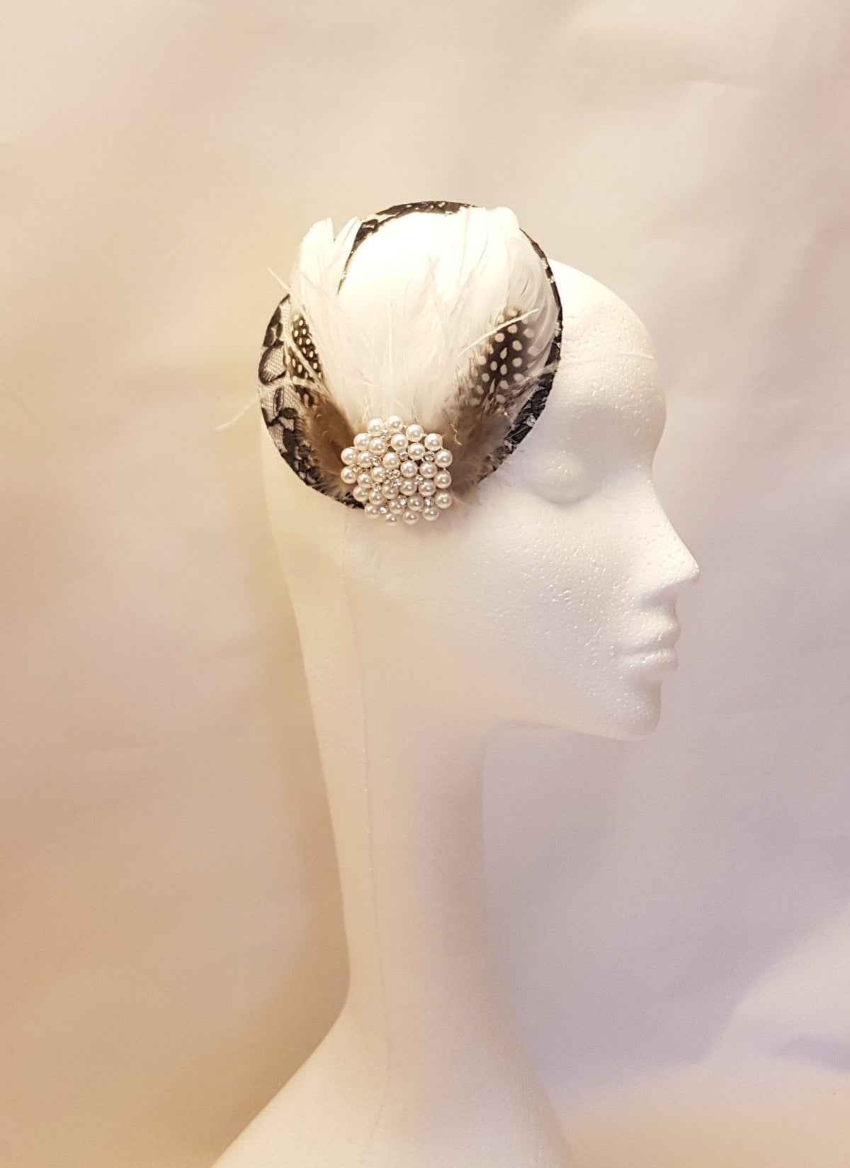 black and white feathered hat with a pearl embellishment.