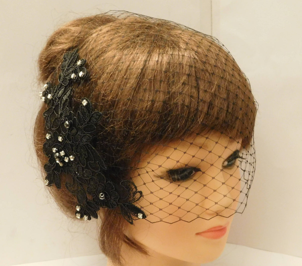 A black lace hairpiece with rhinestones and a black birdcage veil.