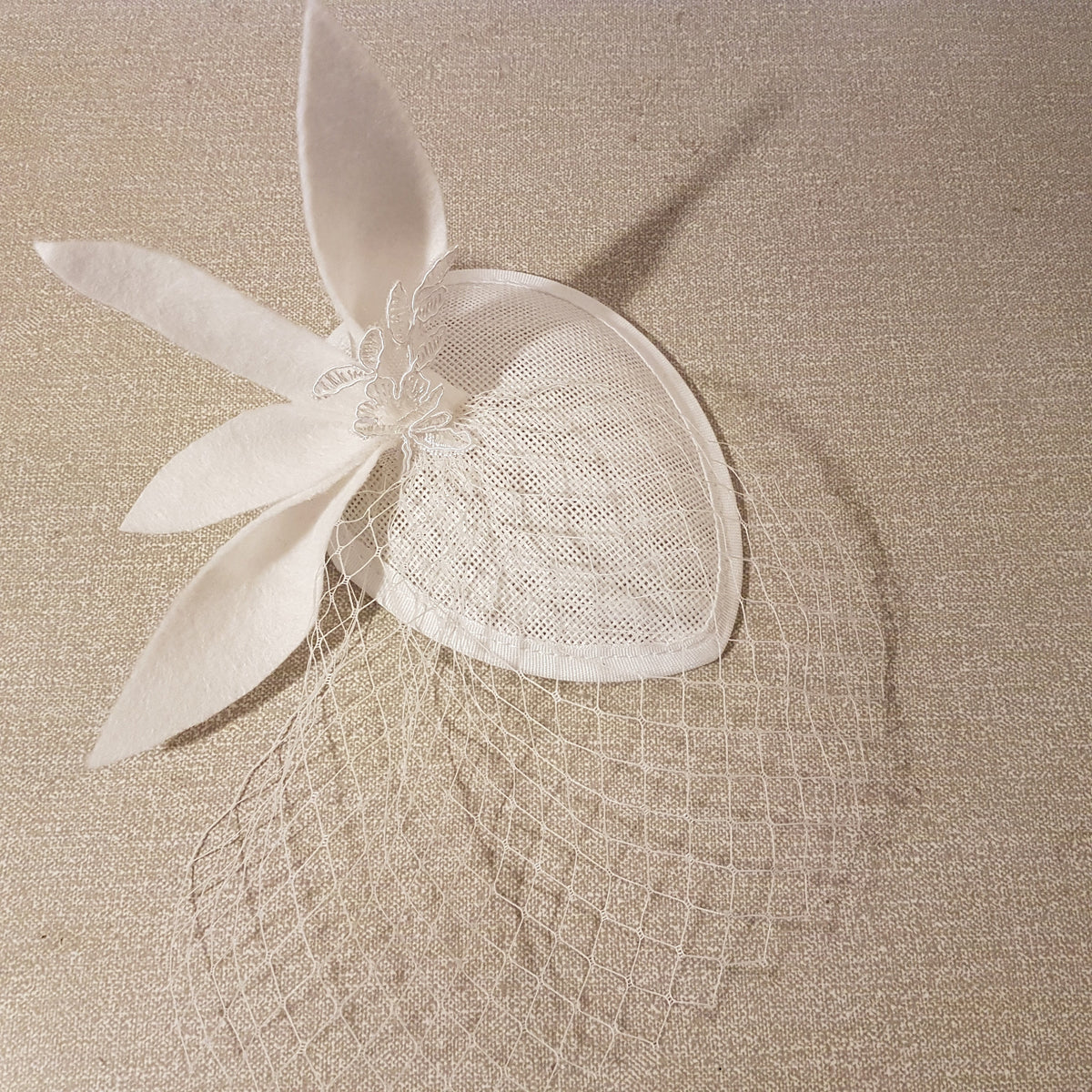 white bridal fascinator hat with a white felt leaves and lace detail design. bridal mini with mini Birdcage veil