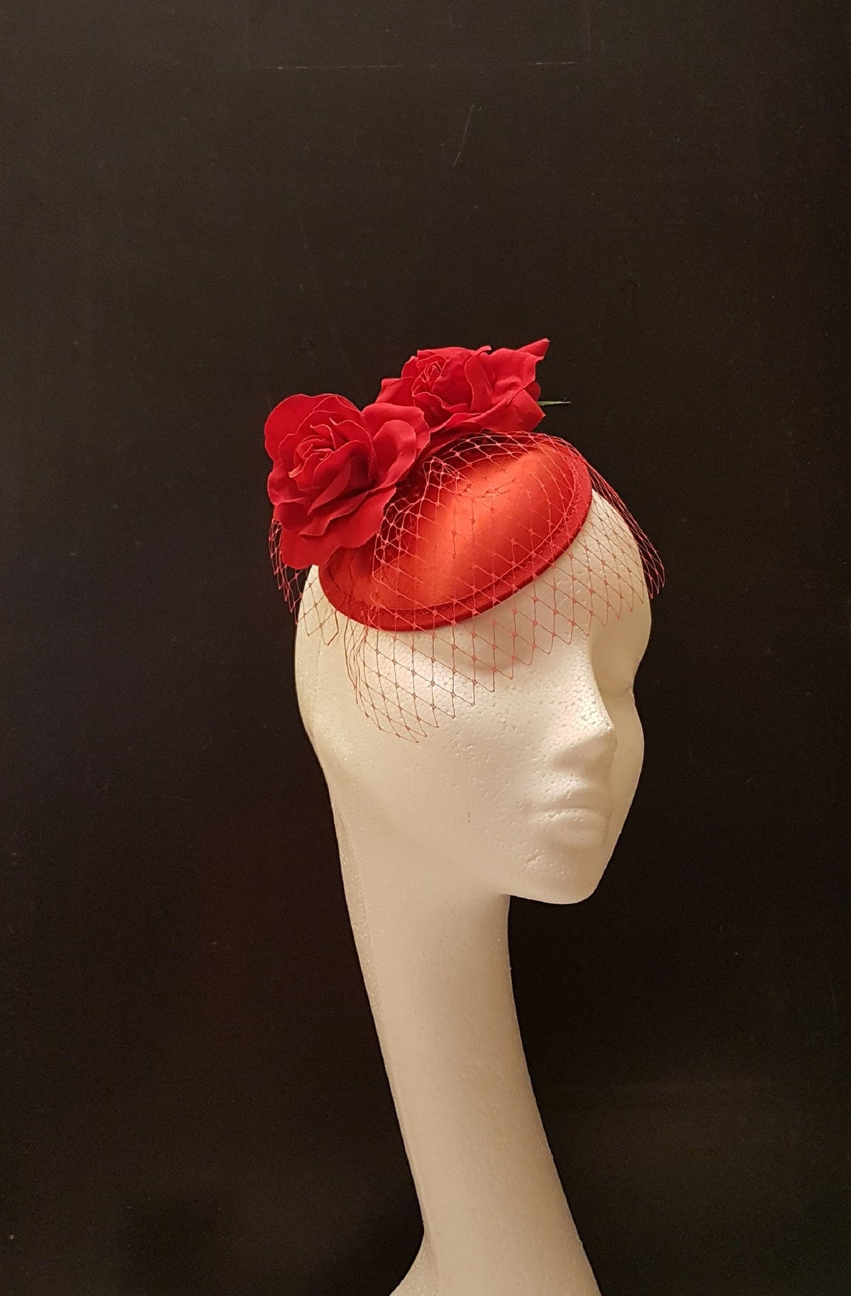 red fascinator hat with a red netting veil and red fabric roses