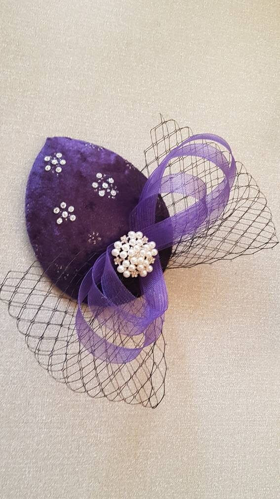 purple velvet hat with a pearl and rhinestone embellishment and a purple and black netting bow.