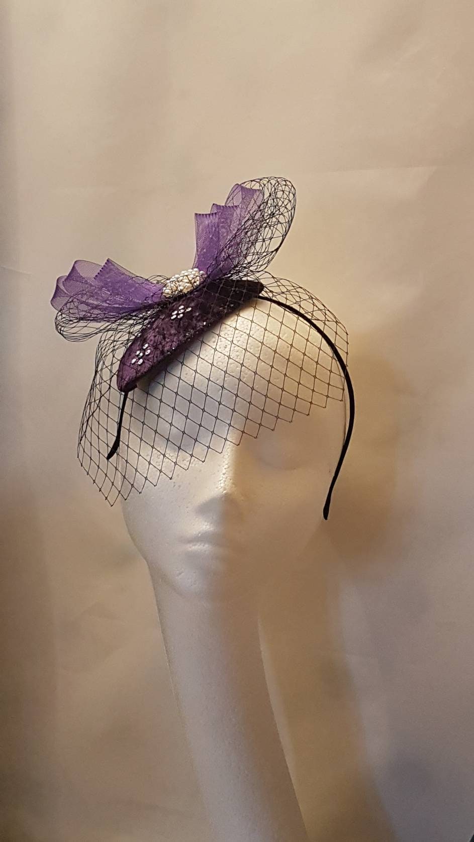 purple velvet hat with a black net veil and a jeweled embellishment.