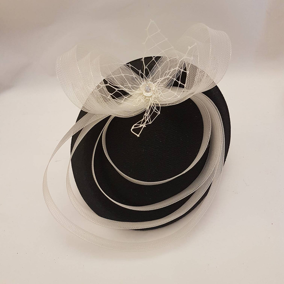black and white hat Facinator a white crinoline bow and a  floral embellishment.