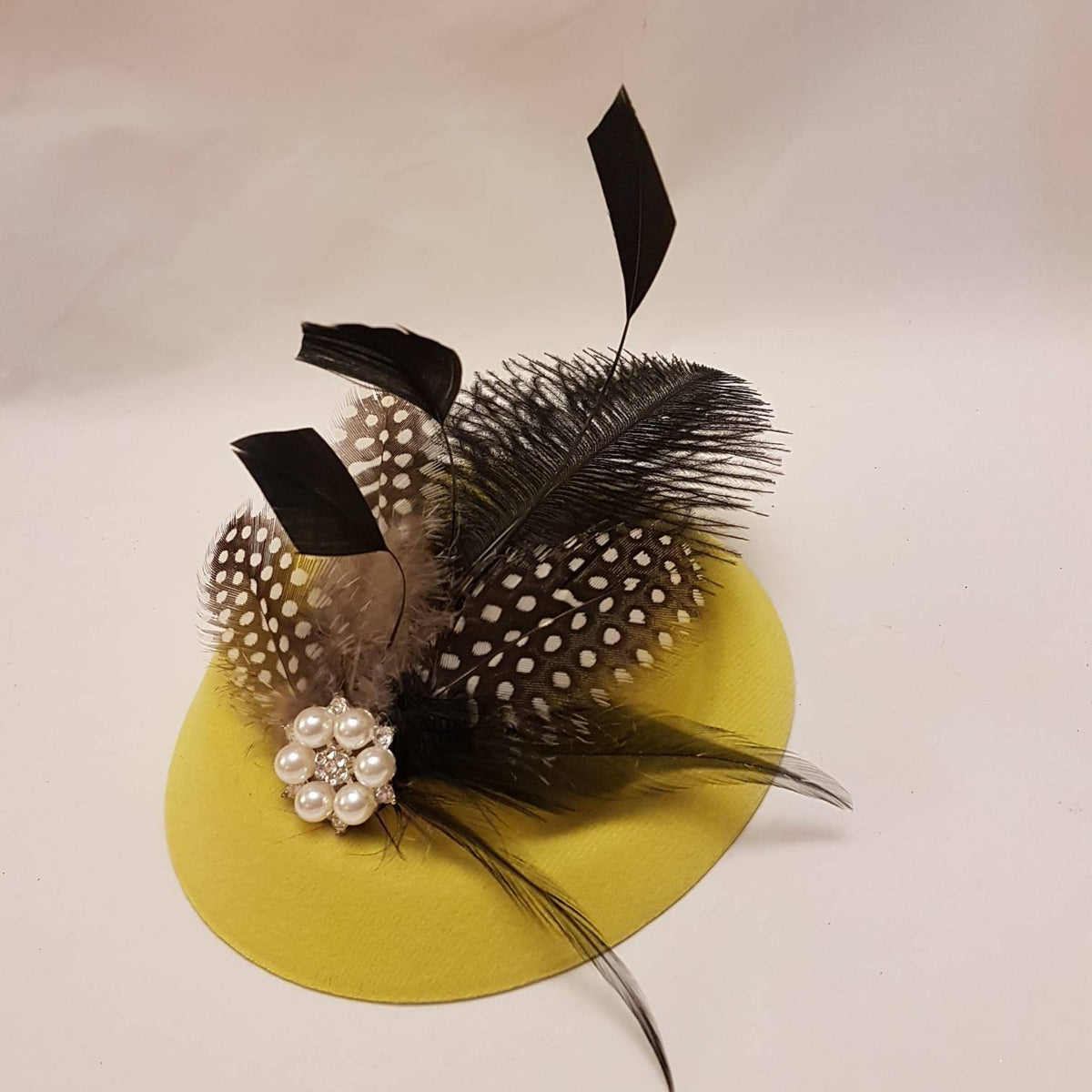 A small yellow hat fascinator with black  feathers and a pearl and rhinestone embellishment for tea party, Ascot  Race,Wedding, and cocktail party
