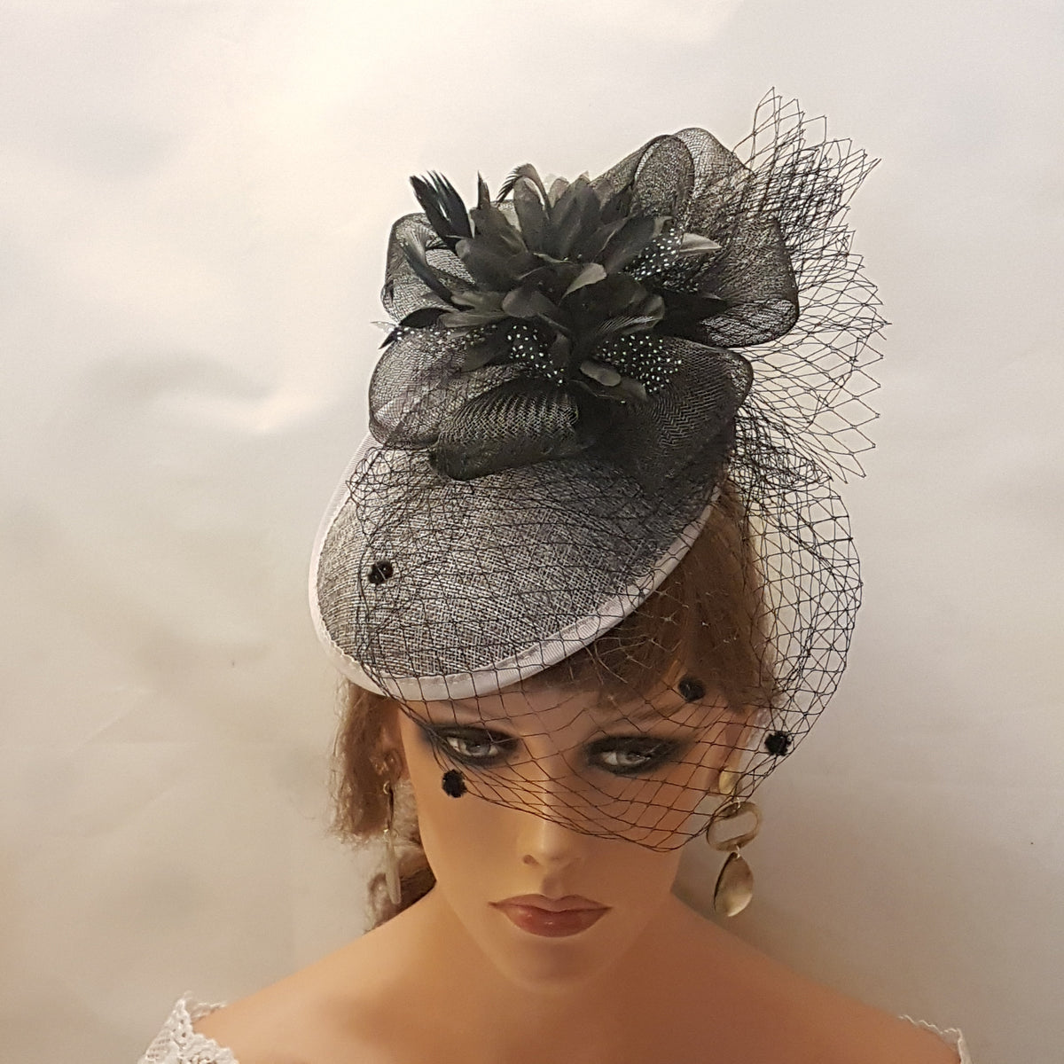 Grey and black fascinator with a black flower and netting.