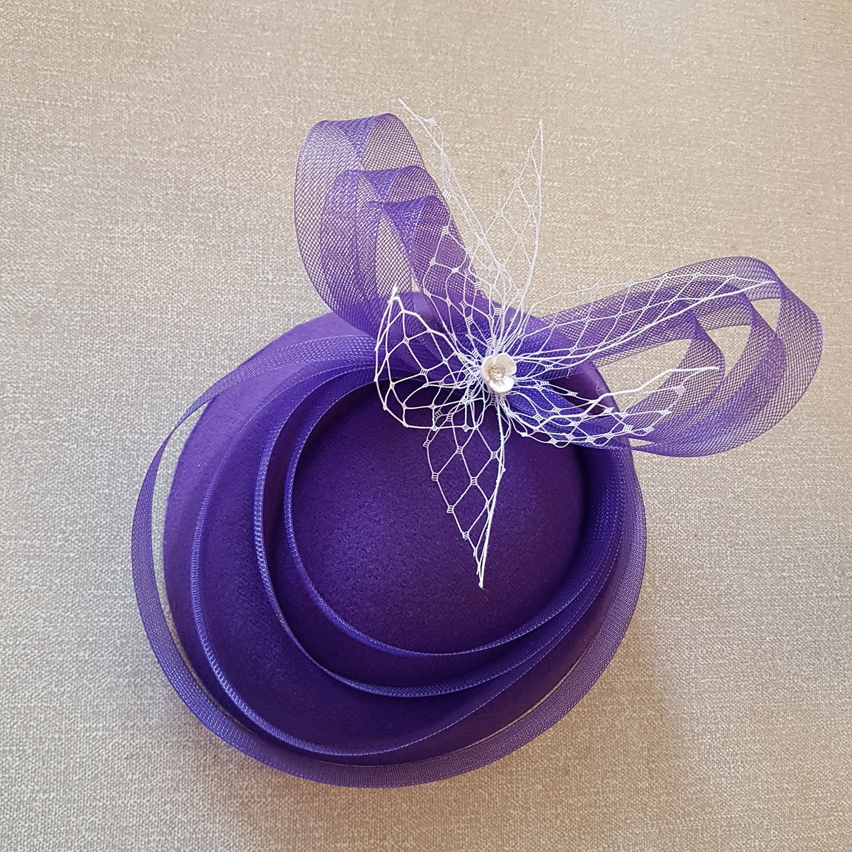 purple felt hat with a white tulle bow and a small rhinestone embellishment.