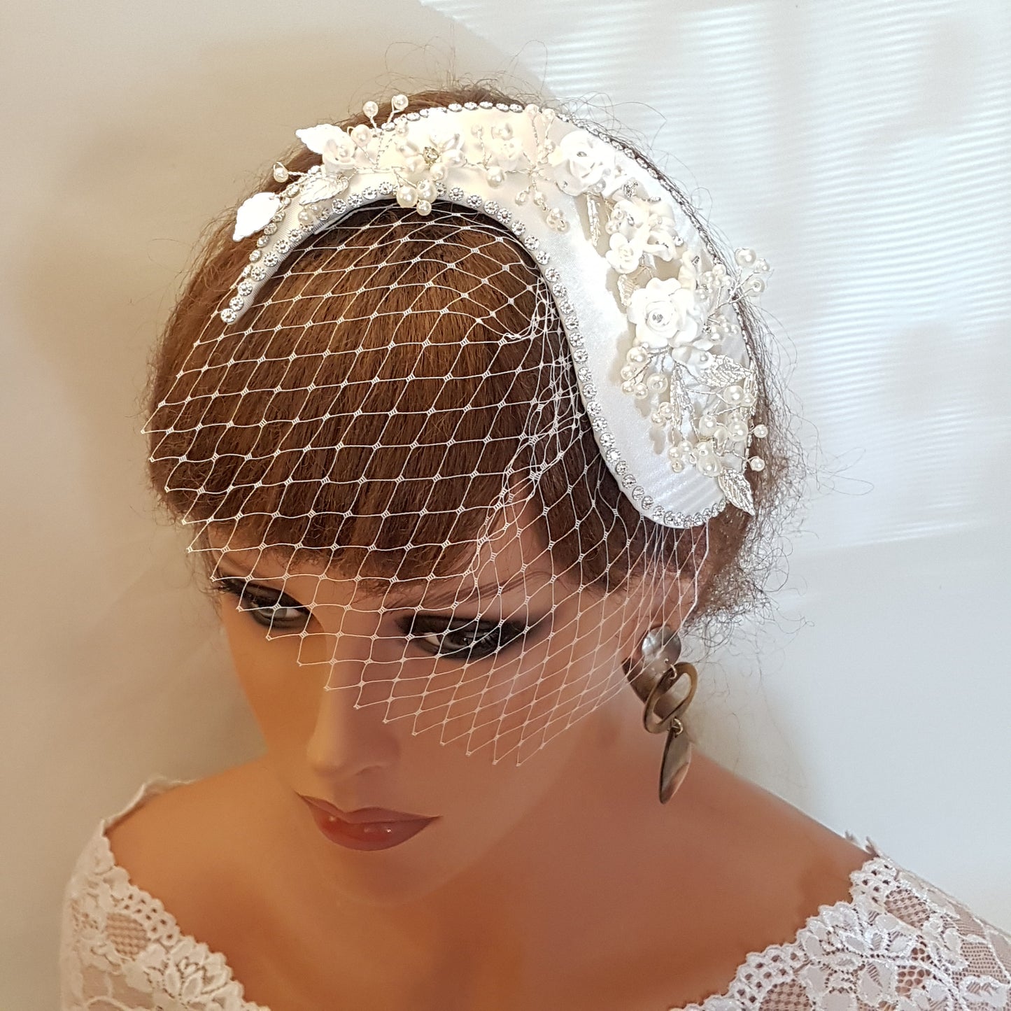 White bridal hair comb with pearl and crystal embellishments and a white birdcage veil.