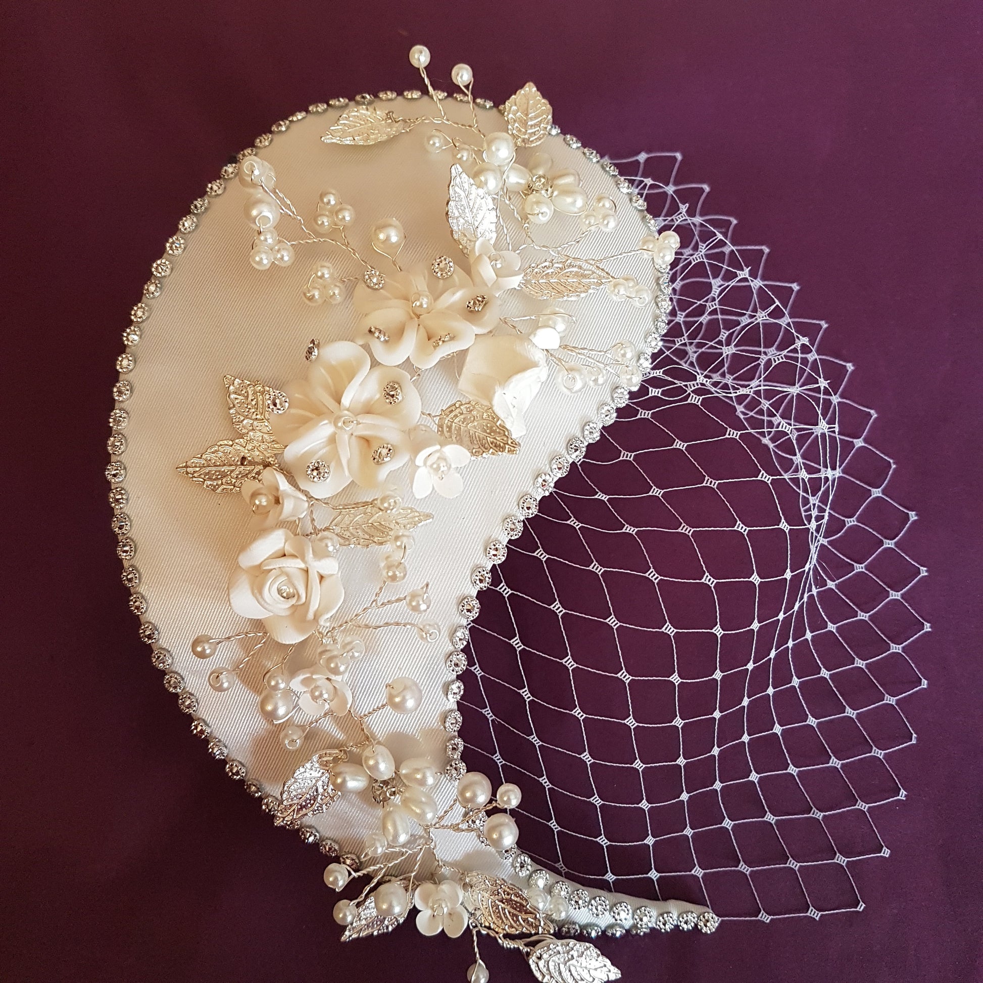 white crescent-shaped bridal hairpiece with pearl and silver embellishments and a white tulle veil.