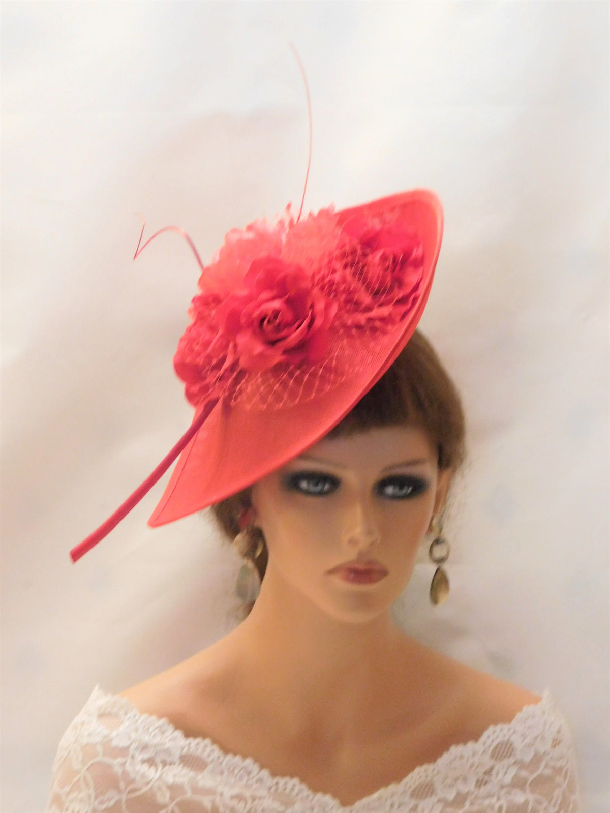 A red hat with a large red flower and a red feather. The hat is made of a soft, delicate material and has a wide brim. The hat is perfect for a special occasion or a day out.