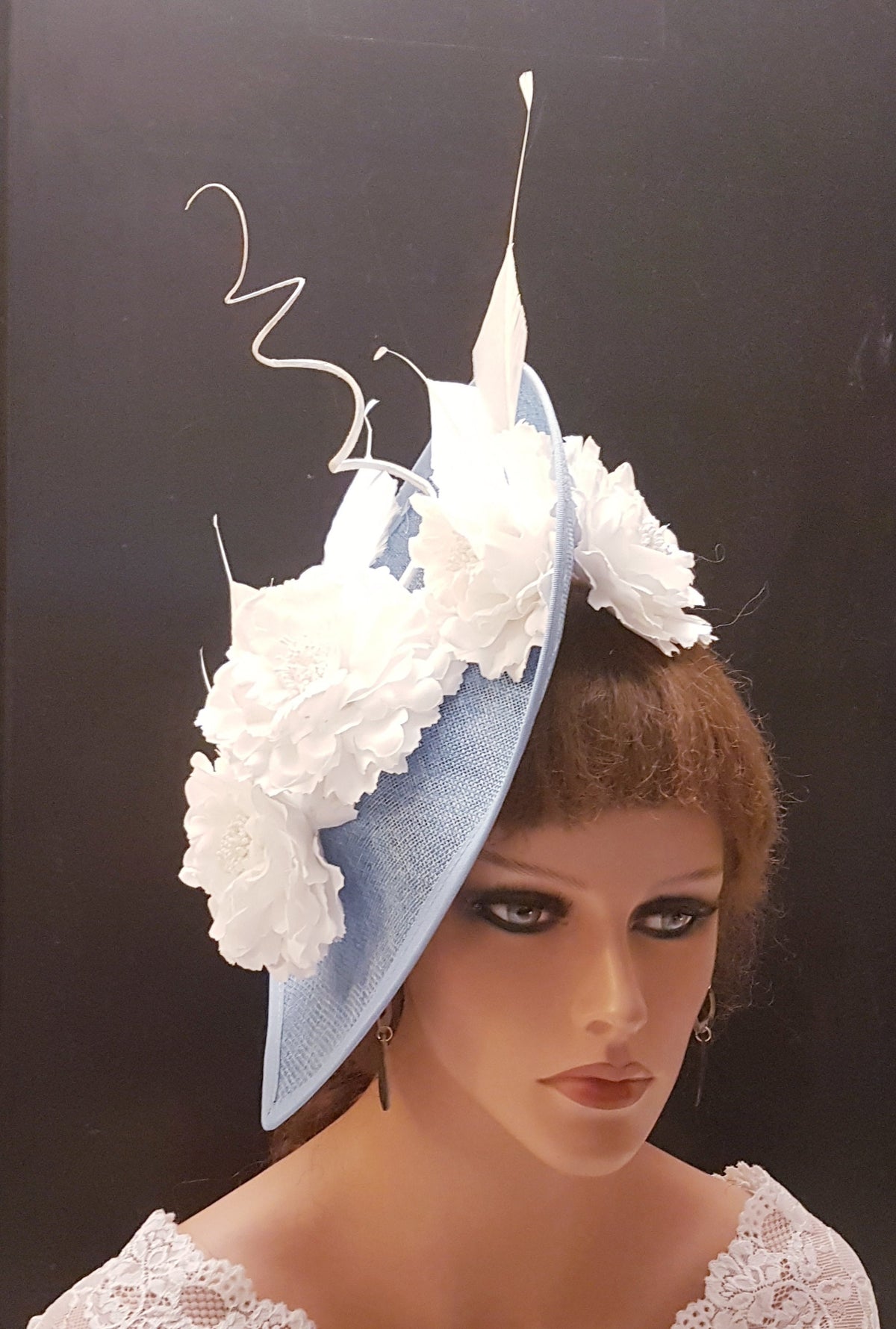light blue hat with white flower embellishments and a white feather accent.