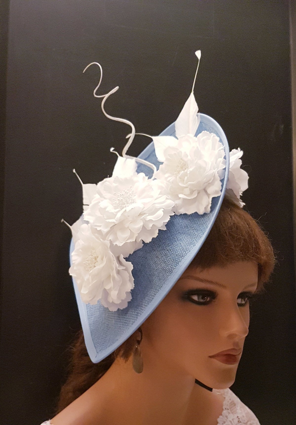 light blue hat with white fabric flowers and a white feather detail.