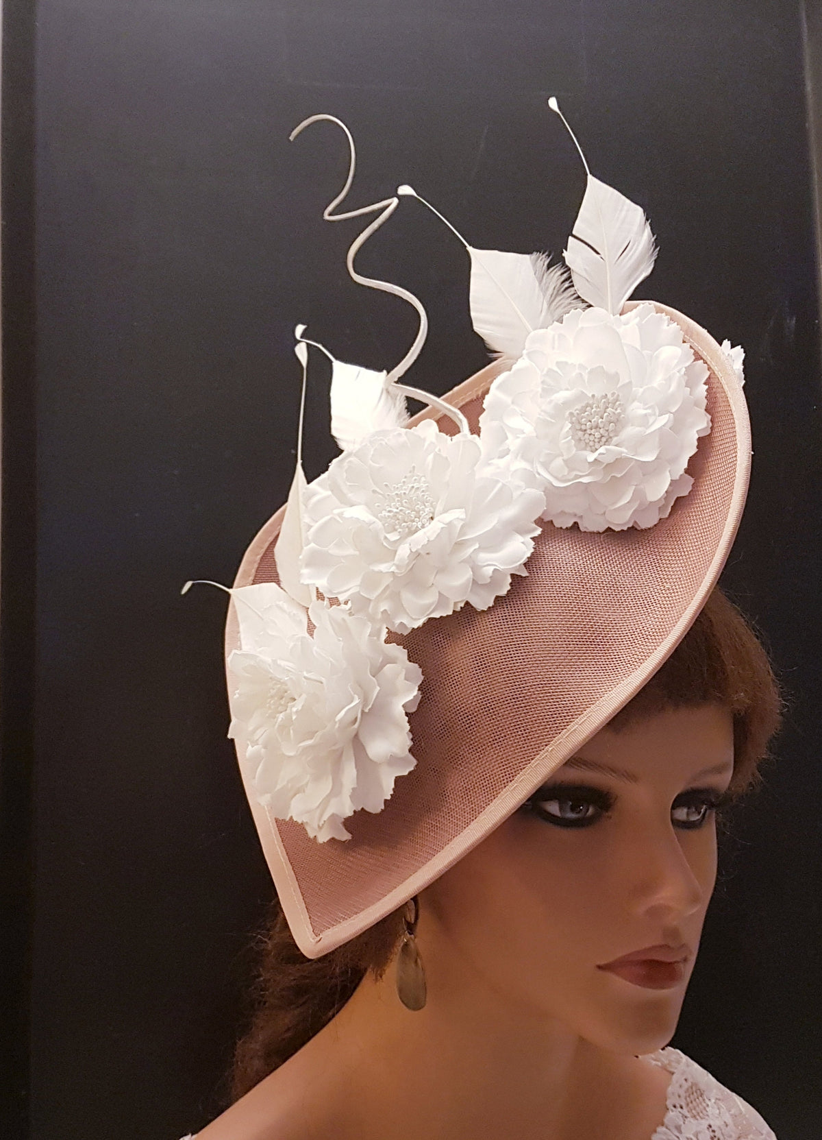 blush pink fascinator with white fabric flowers and feathers. The fascinator has a curved brim and is decorated with three white fabric flowers and feathers.