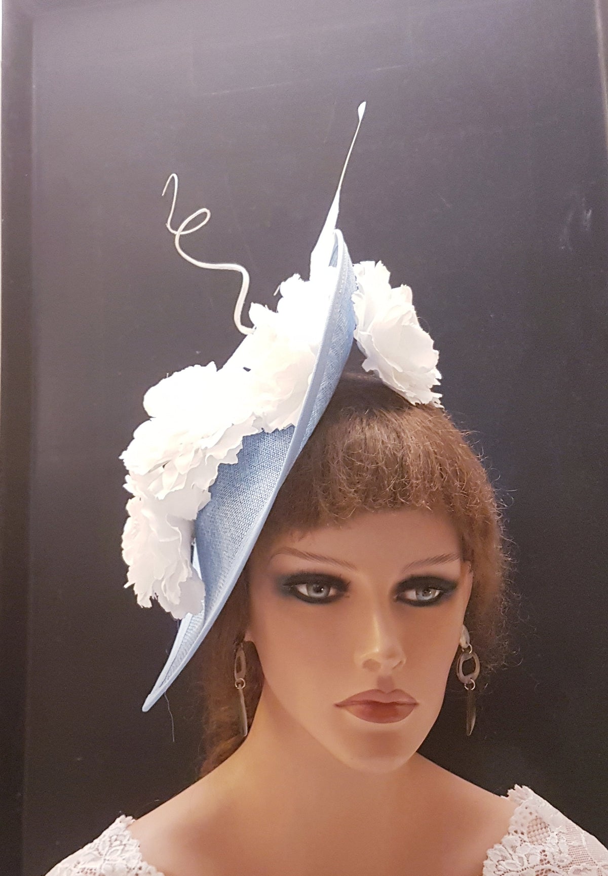 blue hat with white flower embellishments. The hat is angled and has a curved brim.