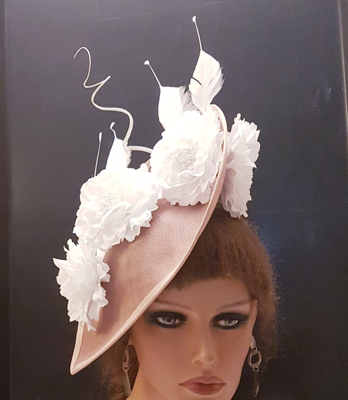 blush pink fascinator with white flower embellishments and feathers.