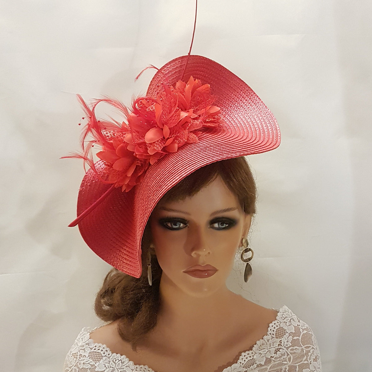 red wide brimmed hat with a red flower and feathers