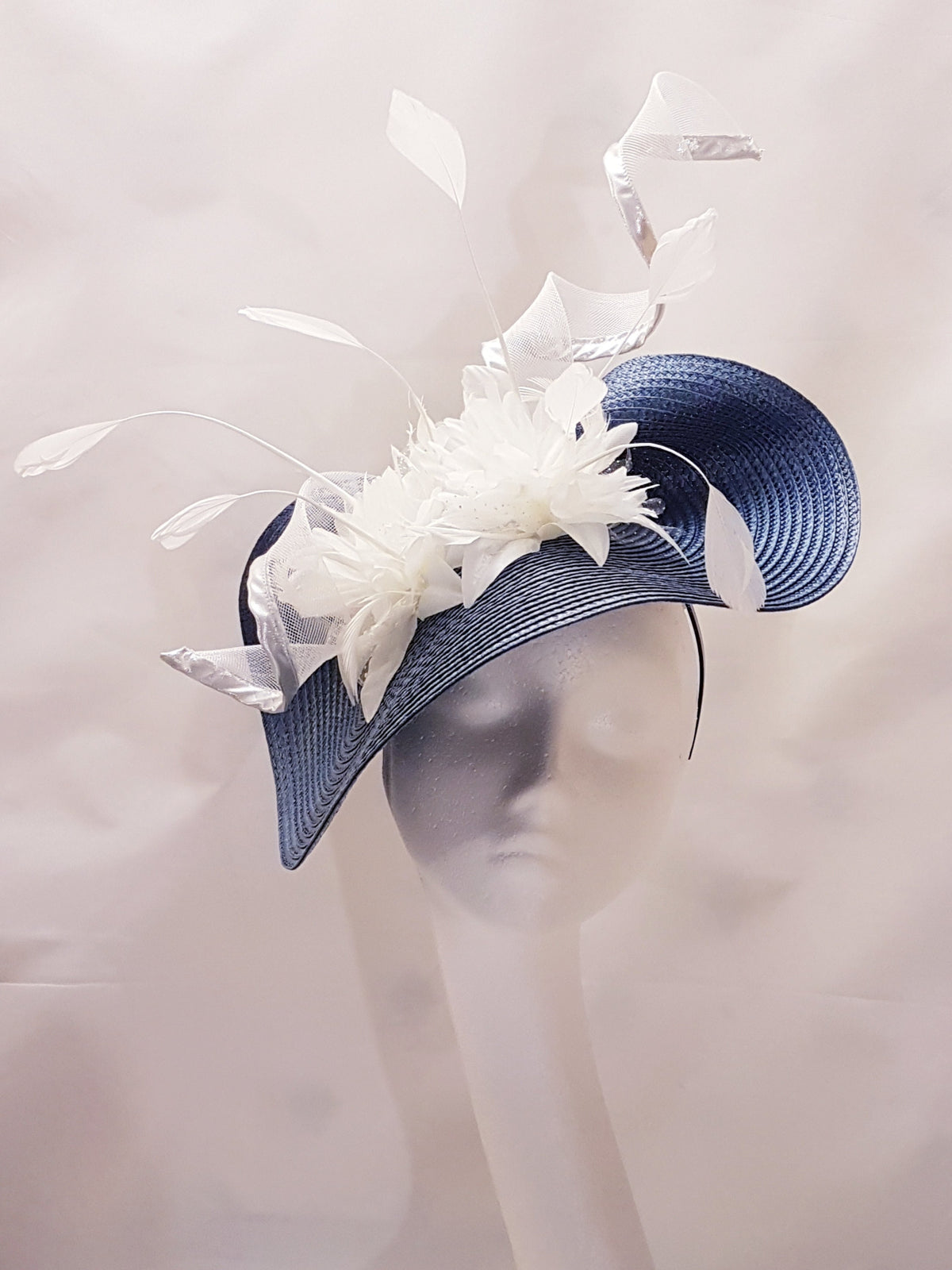blue and white Ascot fascinator hat with a large white flower and feathers.