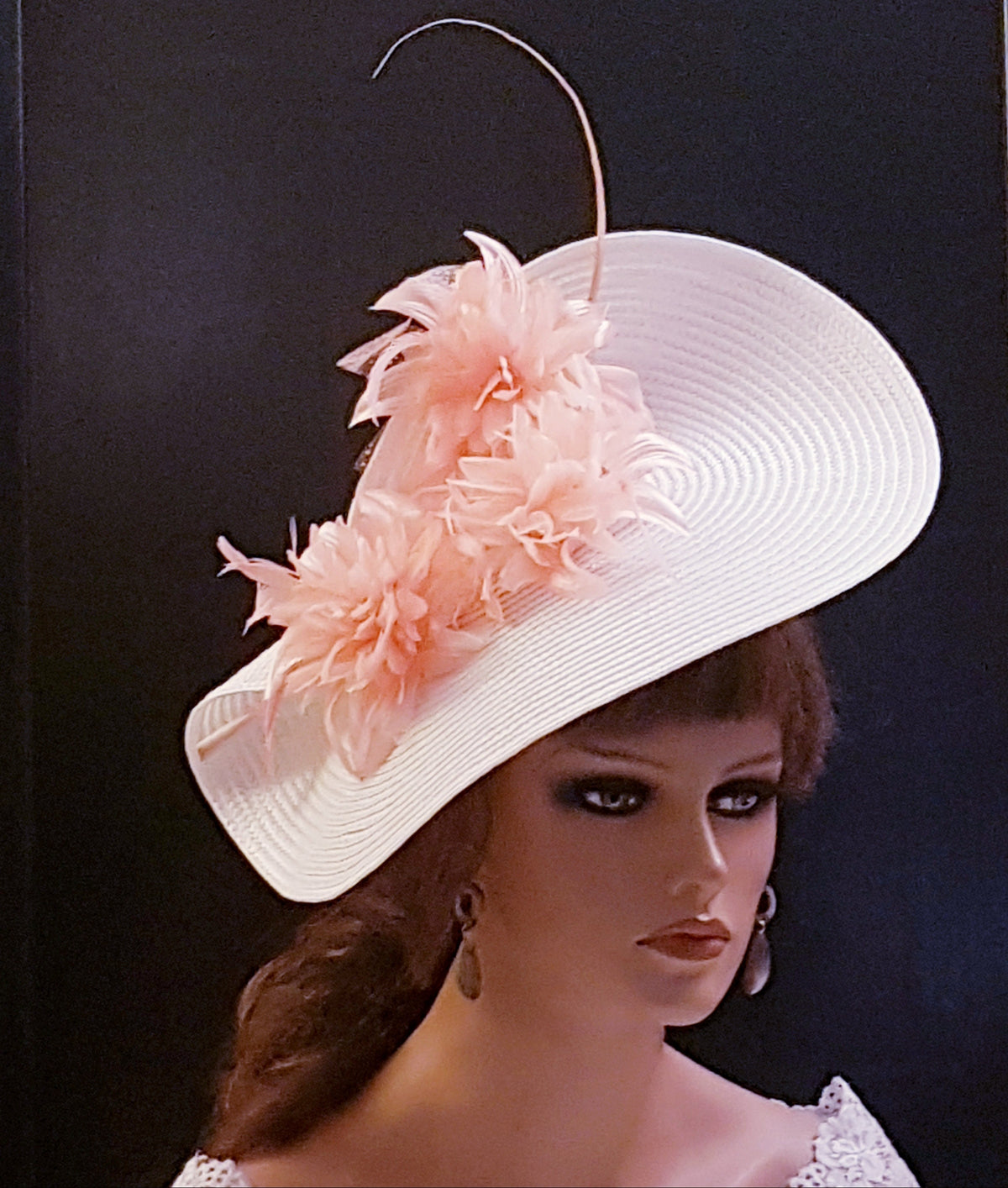A white wide-brimmed hat with a pink flowers and long Quill feathers