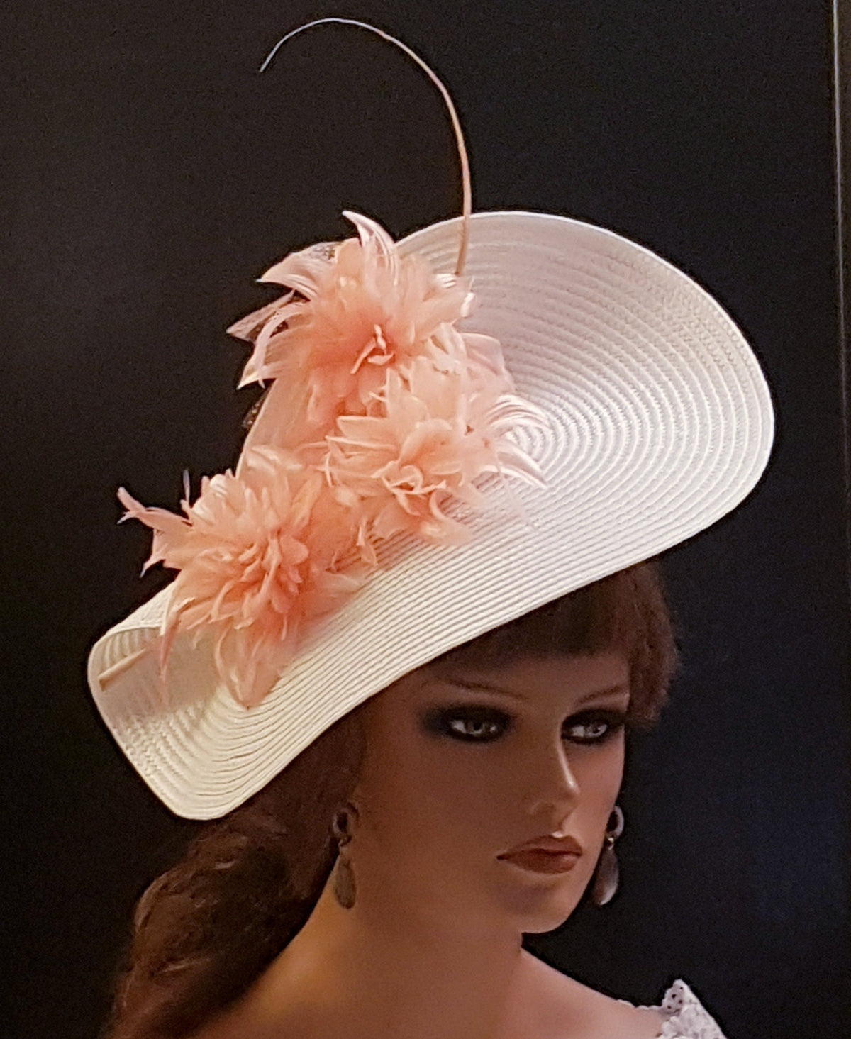 A white wide-brimmed hat with a pink colored flower embellishment for wedding  and Ascot