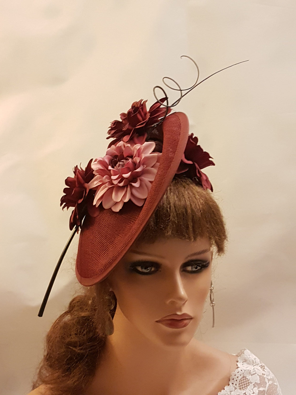 burgundy fascinator with pink and burgundy flowers. The fascinator has a thin black wire that curls at the top.