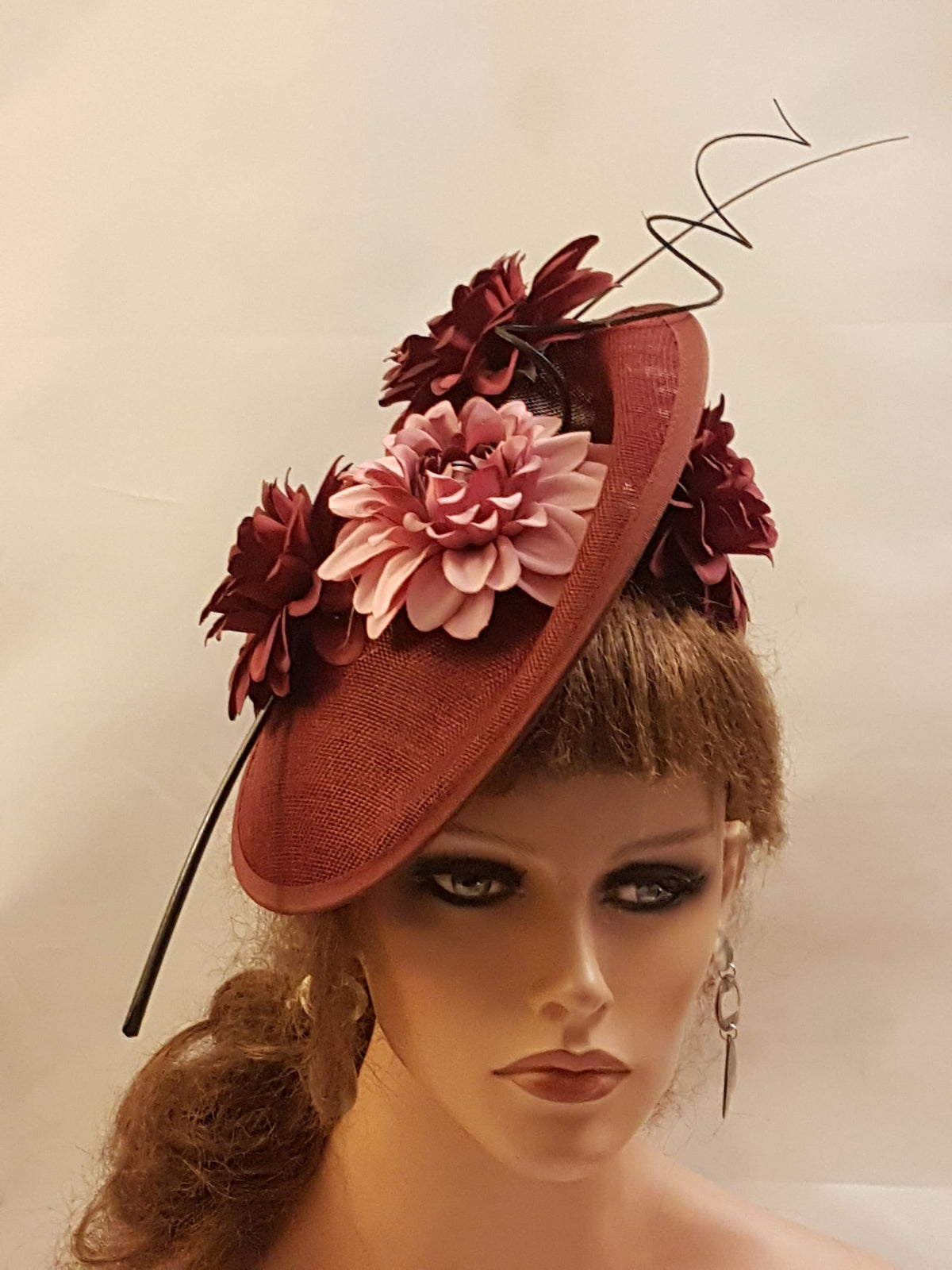 burgundy fascinator with a pink flower and a black wire accent.